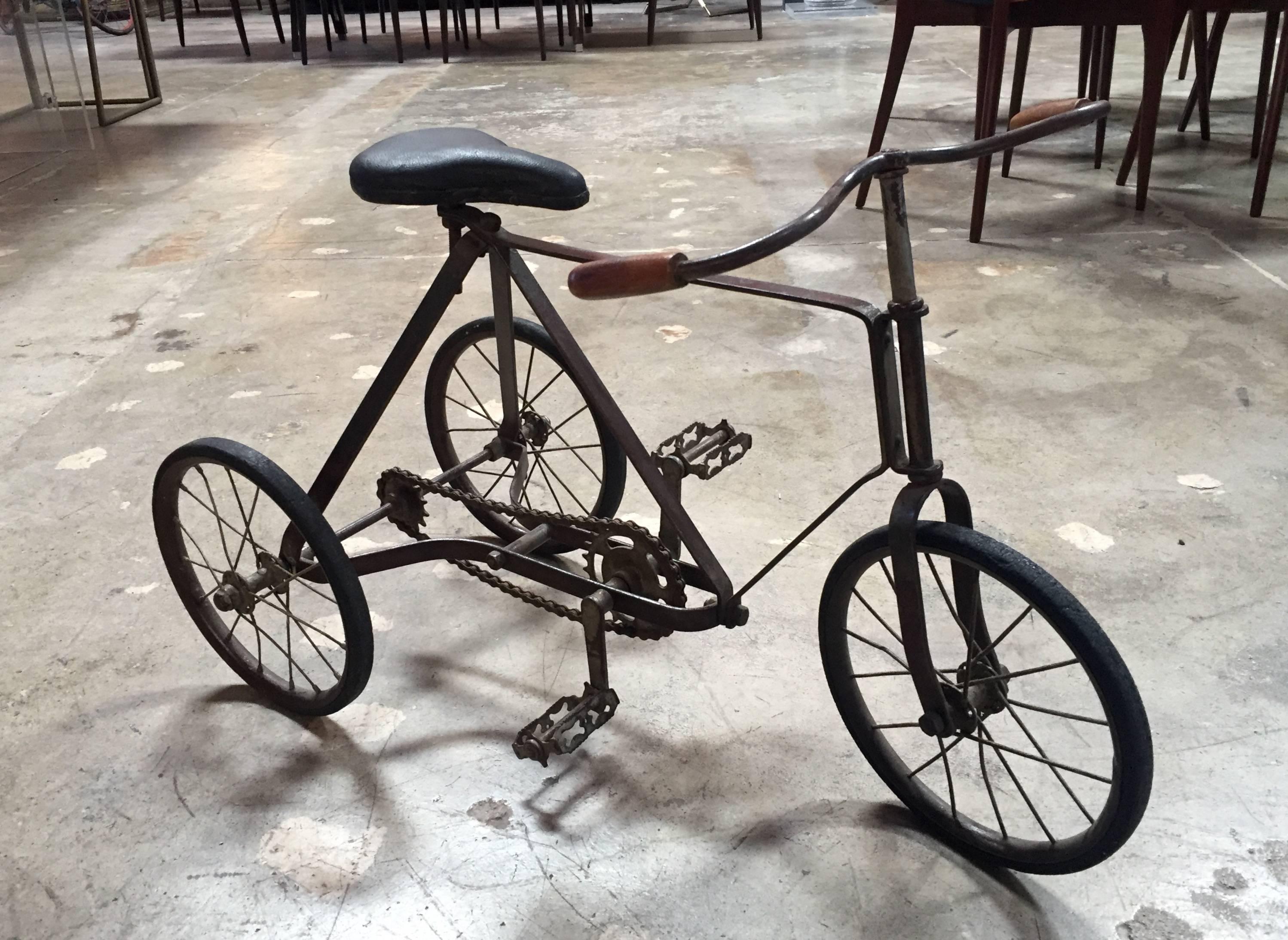 A vintage solid iron tricycle with amazing wooden handles. The item itself is in very good riding condition, even for an adult to use! Distressed, vintage condition reflects in the patina and in the charming signs of age and character.
     