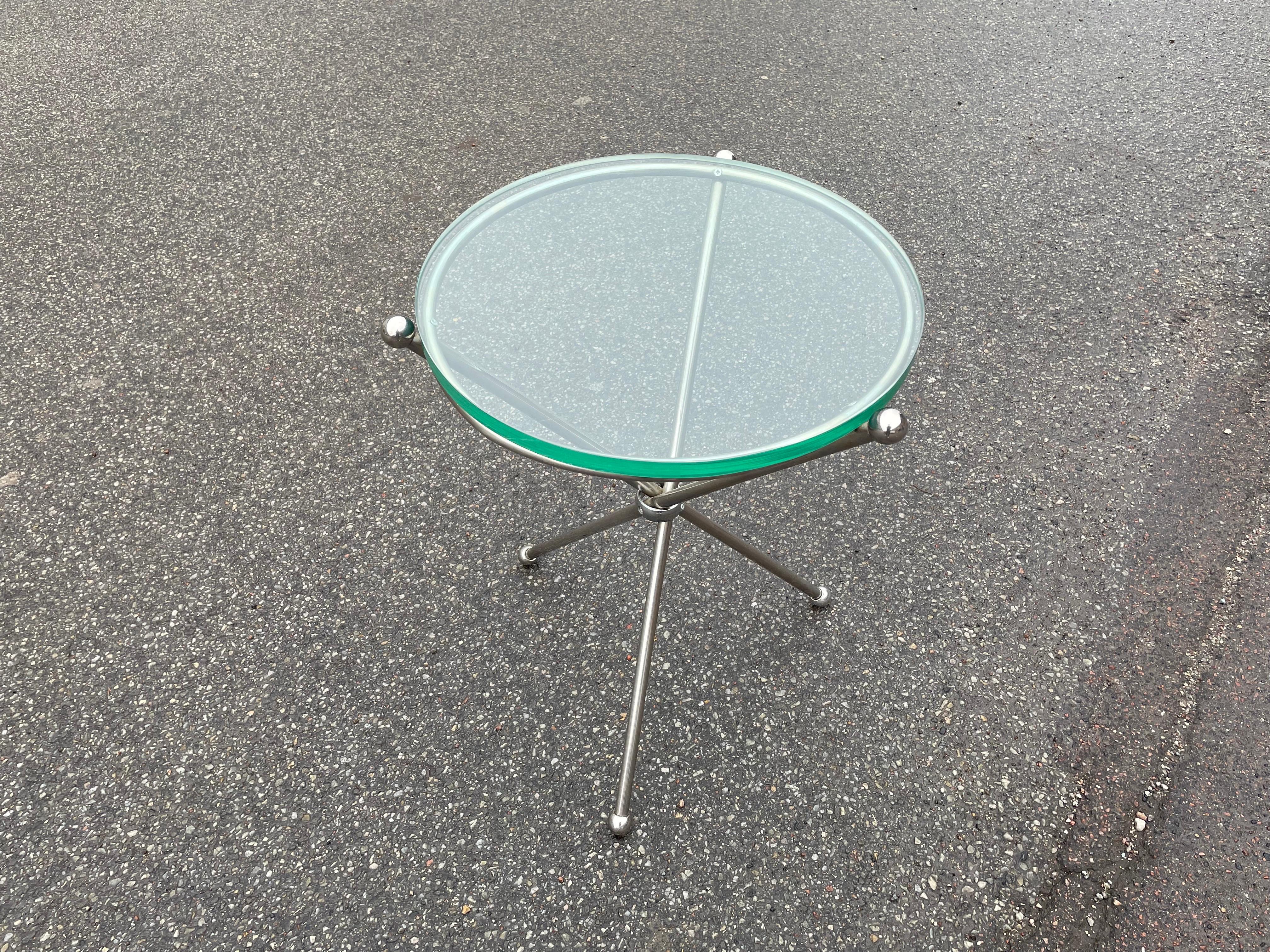 Italienischer Beistelltisch aus Silberblech, elegant und ungewöhnlich. Die Beine haben kleine Kugeln an der Unterseite. Die Glasplatte ruht auf anders geformten Kugelpfosten. Der Durchmesser des Glases beträgt 47 cm