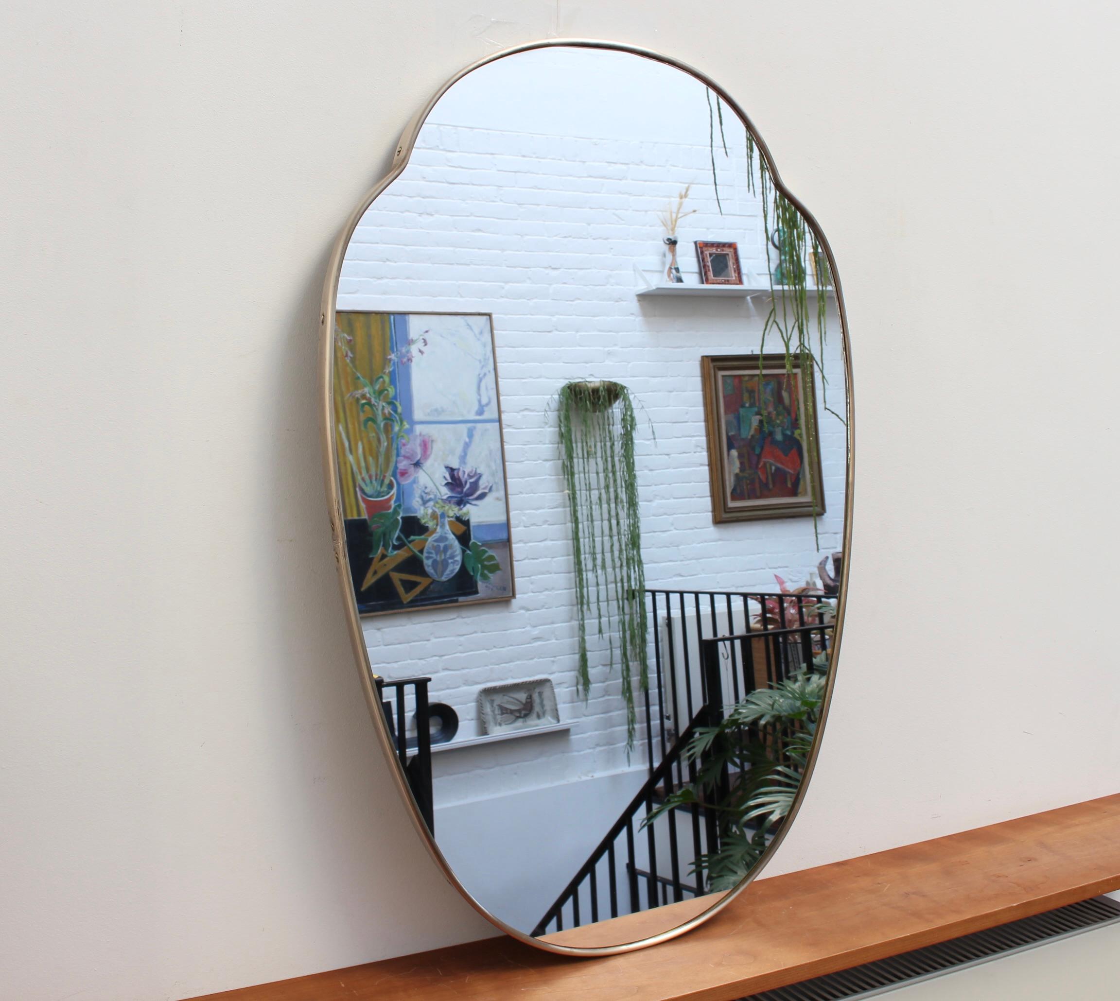 Mid-century Italian wall mirror with brass frame (circa 1950s). The mirror is classically-shaped and distinctive in a Modern style. It is in very good overall condition. A beautiful, aged patina on the recently polished brass frame attests to the