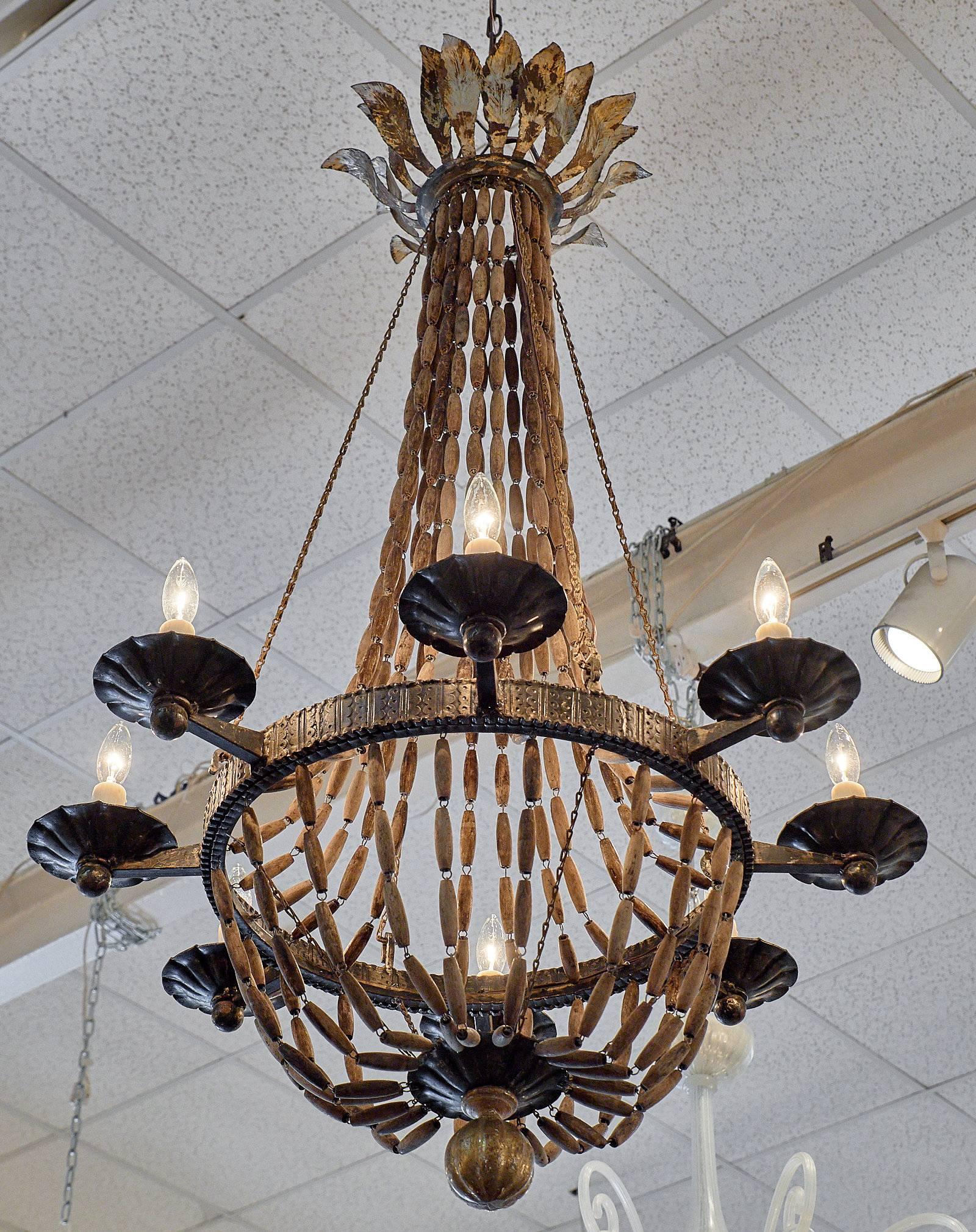 An important Italian chandelier of hand-hammered forged iron, wooden beads and chain. This piece has eight branches and has a gold leafed finial. It is wired to fit US standards. This unique fixture will steal the show in your living area!