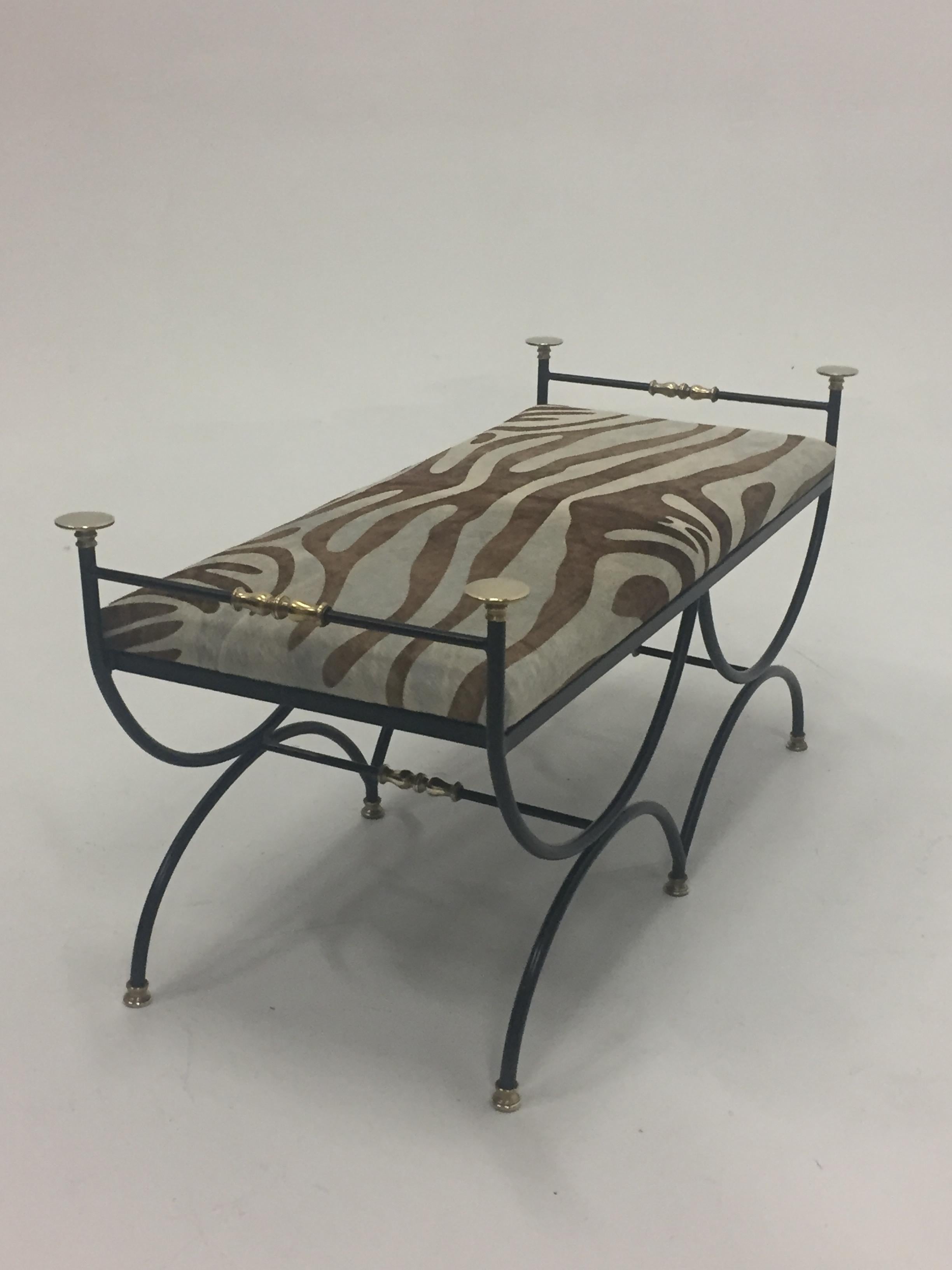 Handsome vintage rectangular bench having hand forged black wrought iron base with
brass finials and details, newly upholstered in zebra print cowhide.