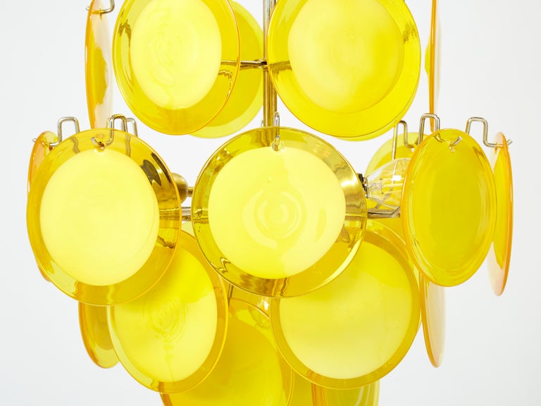 Beautiful Italian style and high quality manufacturing for this mid-century chandelier designed by Vistosi in the late 1970s. It features 24 yellow discs made of Murano glass, and 4 lights. This chandelier will be ideal to highlight a cute bedroom,
