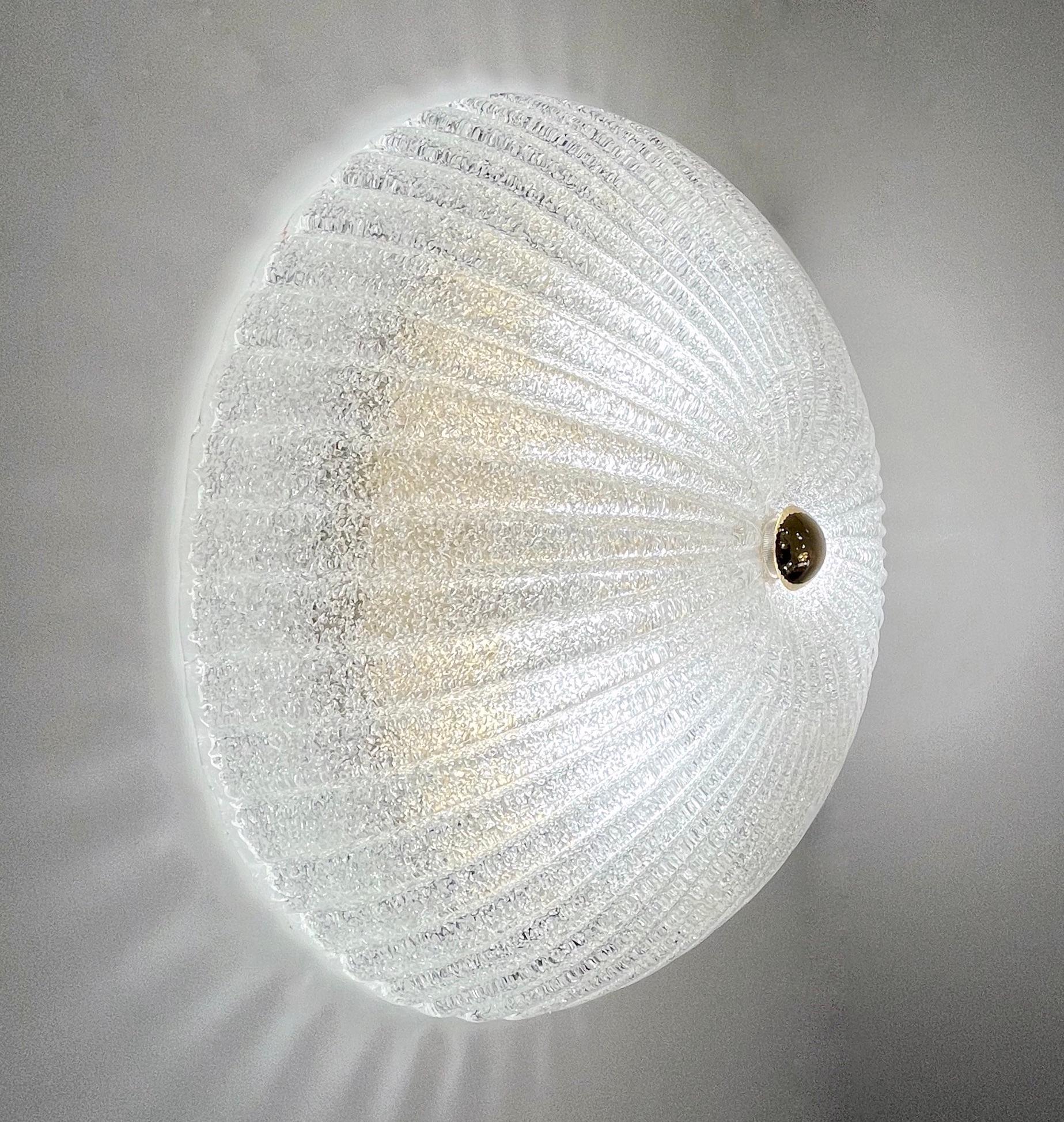 A contemporary pair of Mid-Century Modern style crystal clear Murano glass wall lights, can also be mounted as flush mounts, entirely handcrafted in Italy, the reeded glass bowls blown on the Murano island, signed Vistosi, is elegantly frosted with