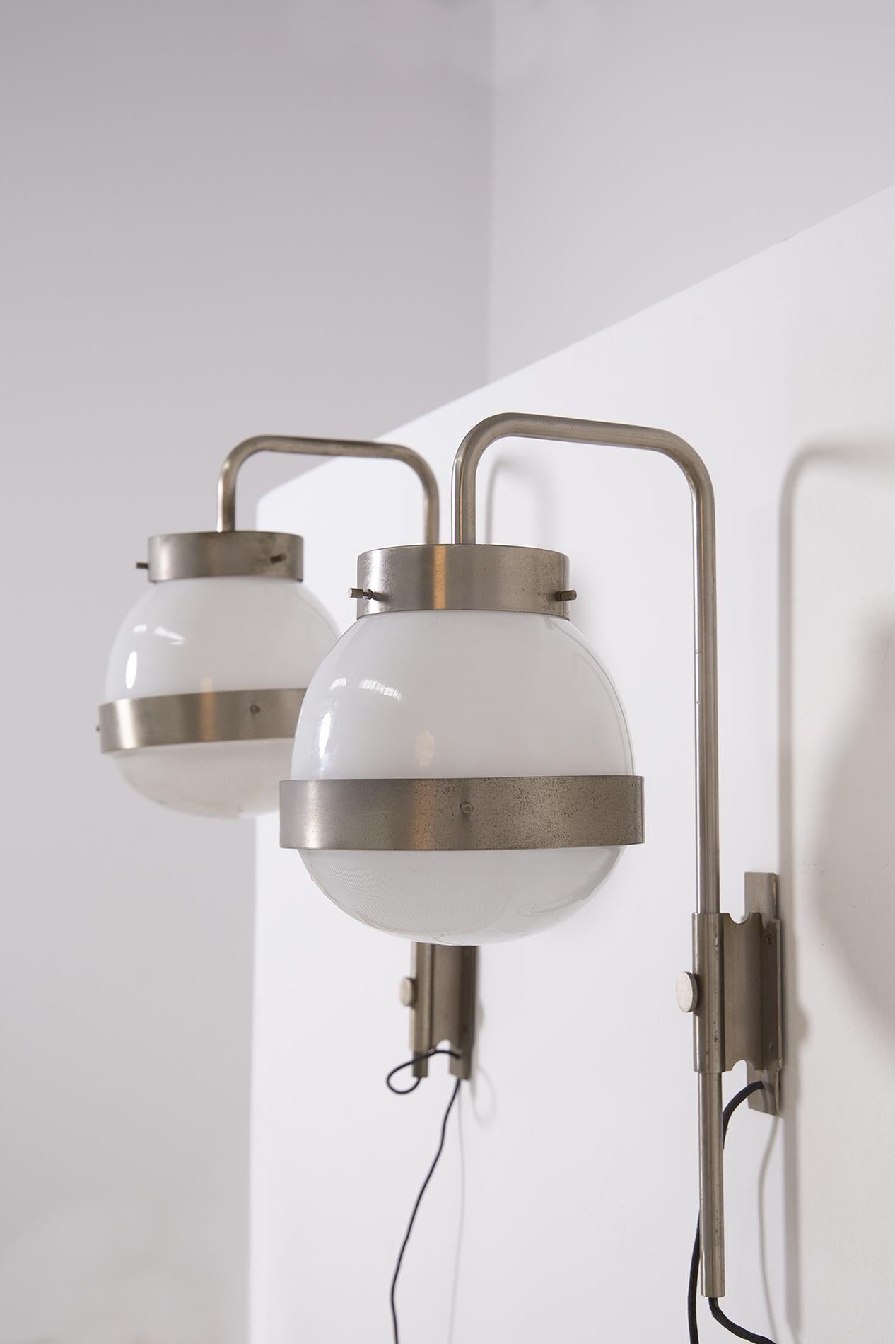 Pair of wall sconces designed by designer Mazza Sergio for Artemide manufacture in 1960. The wall lights are the Delta model and are adjustable in height thanks to its knob mechanism that allows the adjustment. The lamps are wall lamps. The