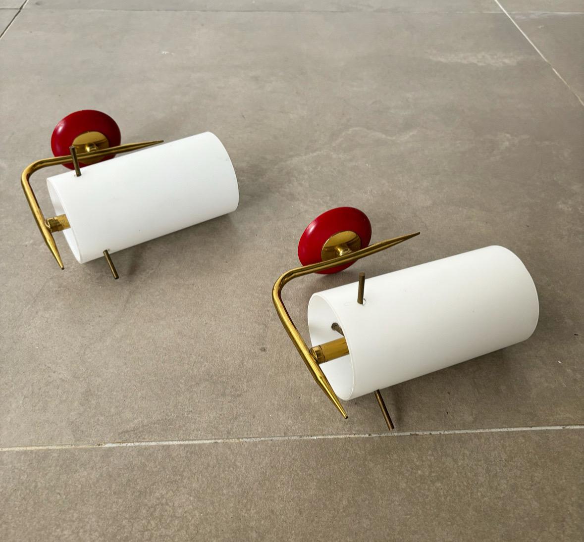 These rare Italian wall lights from the 1950s embody the elegance and craftsmanship of midcentury modern design. Constructed with a combination of brass, red lacquered metal, and milk glass, they exemplify the era's penchant for bold yet refined