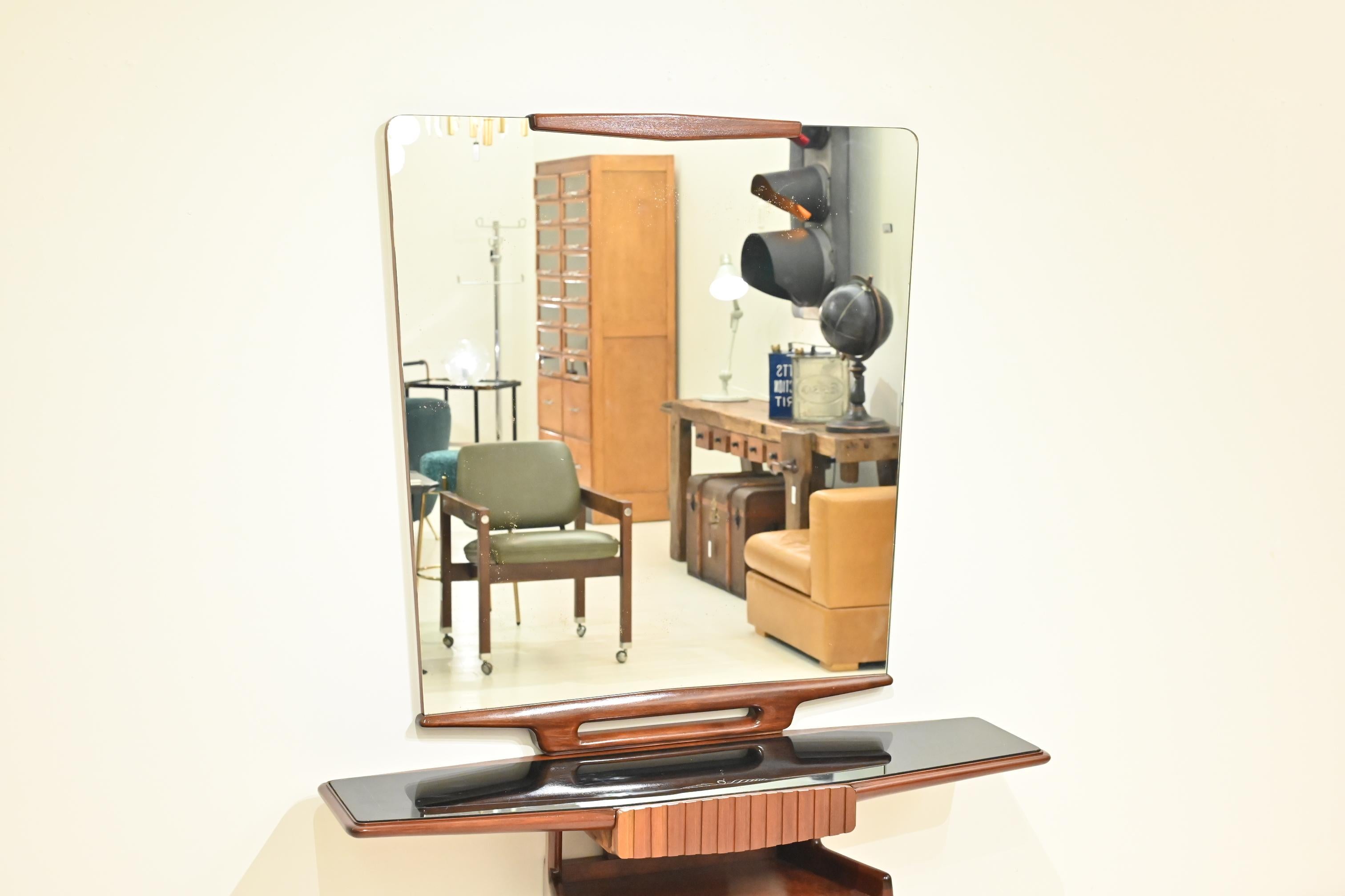 This is a stunning set of an Italian vintage wall mirror and console table, estimated to be from the 1950s.
The piece combines a retro silhouette with futuristic detailing, creating a unique visual presence. Most notably, the mirror exudes a bold