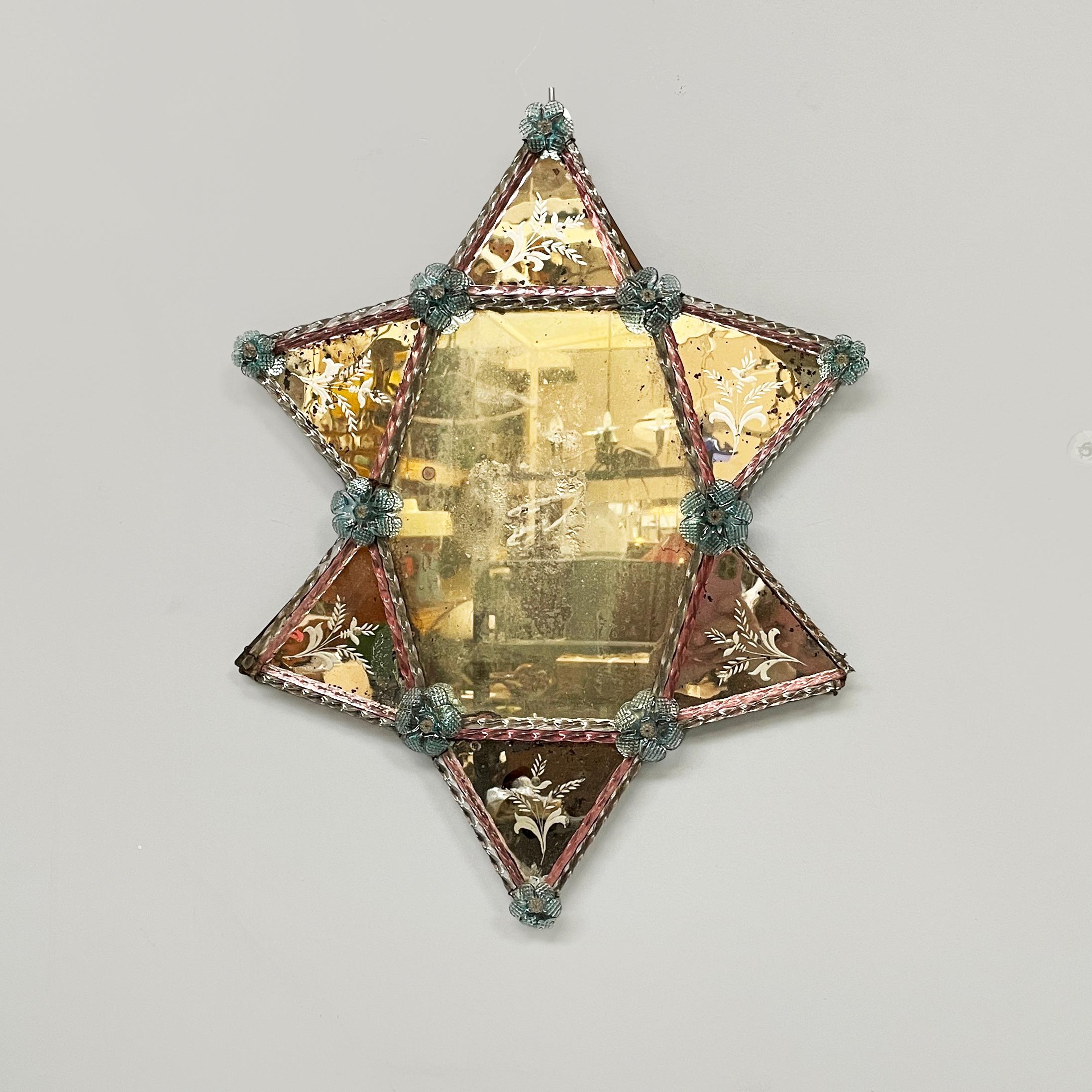 Italian wall mirror with glass decoration and acid etchings, 1980s
Geometric wall mirror with colored glass decorations. The central hexagonal mirror has triangular mirrors with acid etchings on the sides. The mirror profiles have decorations in