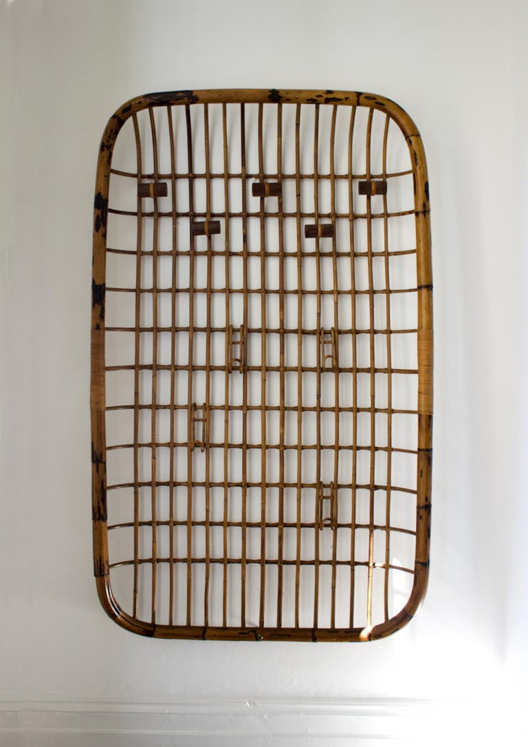 A large wall-mounted coat rack with nine hanging points. Mid-20th century, Italy. Unsigned, very much in the style of Olaf Von Bohr.

The frame and structure of the piece are of bent bamboo, bound with rattan; there are five large hanging points