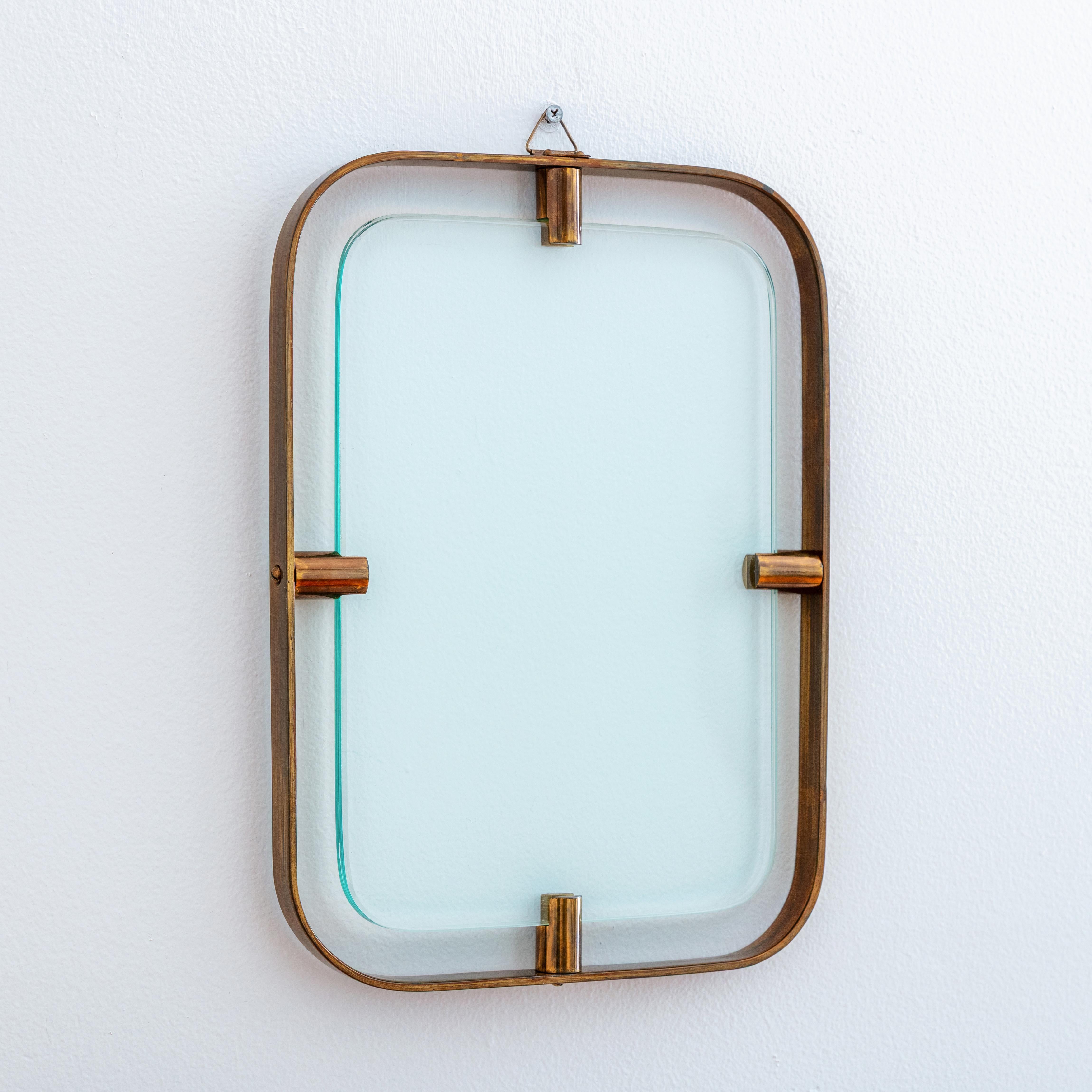 Excepcional marco colgante compuesto por 2 placas de cristal con bordes biselados que flotan dentro de un sólido marco de latón de grueso calibre, todo ello con esquinas redondeadas. Tan llamativo que casi funciona como arte mural sin necesidad de