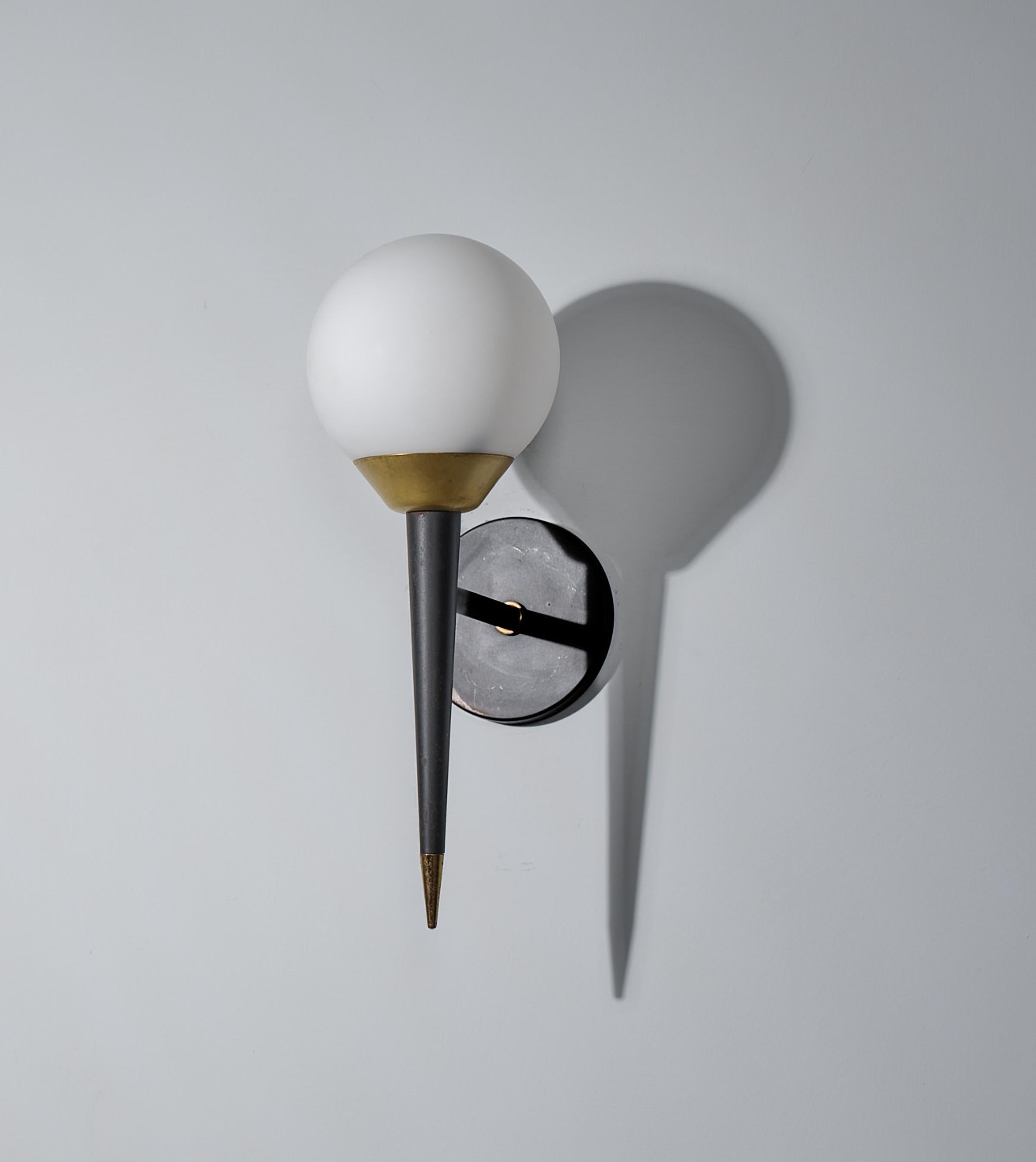 Offered here is an elegant Italian wall lamp from the 1950s, embodying the sleek and sophisticated design characteristic of the era. The sconce features a minimalist black enameled steel mount supporting a spherical opaline glass shade that diffuses
