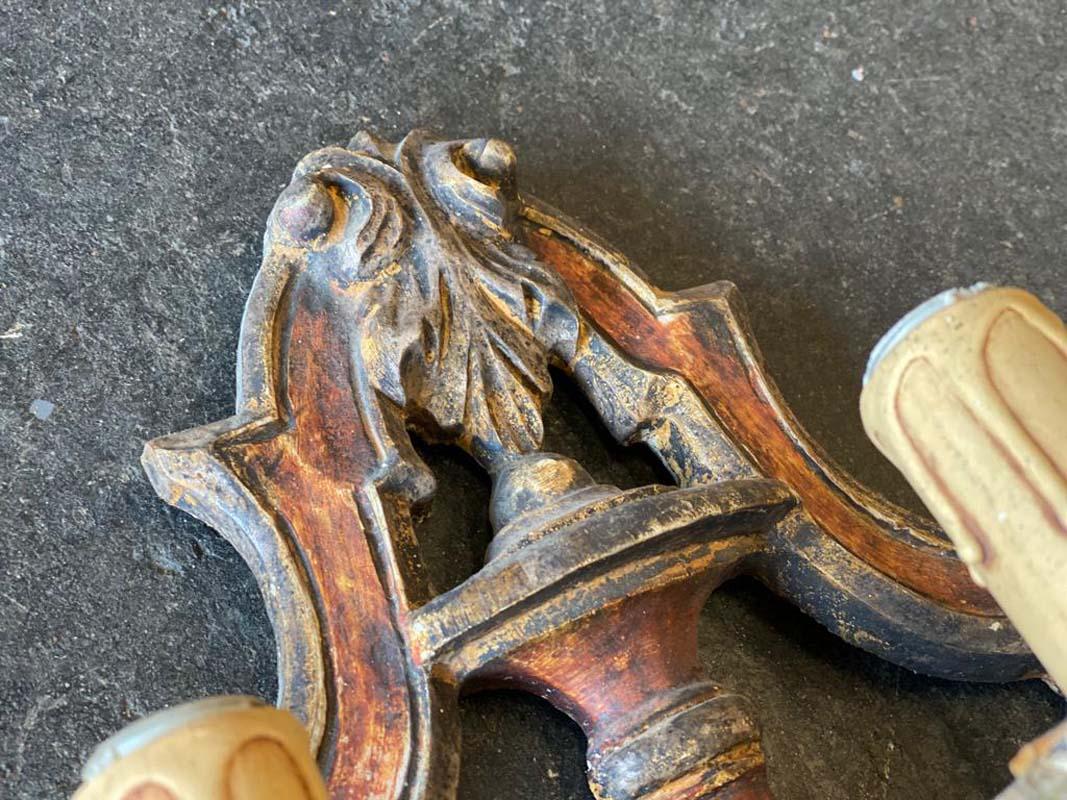 Italian wall sconce /baroque carving. The elaborate sconce has 3 arms, each with a spout in the shape of a candle with original sockets. The chandelier arms are held together by a decorative metal rosette and connected to the wood carving.

A