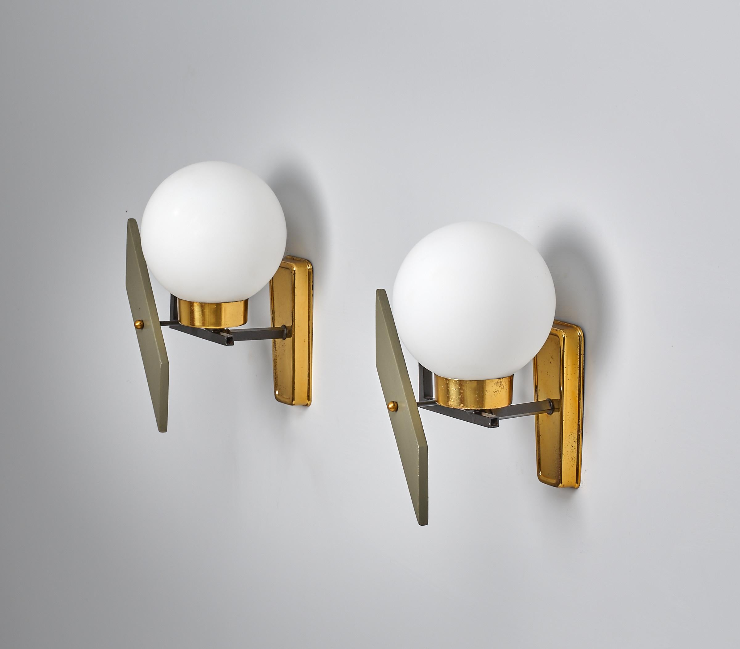 Dieses elegante Paar Wandleuchter aus der Mitte des Jahrhunderts spiegelt die Finesse des italienischen Designs der 1950er Jahre wider. Jede Leuchte zeichnet sich durch eine harmonische Mischung von Materialien aus: poliertes Messing mit natürlicher