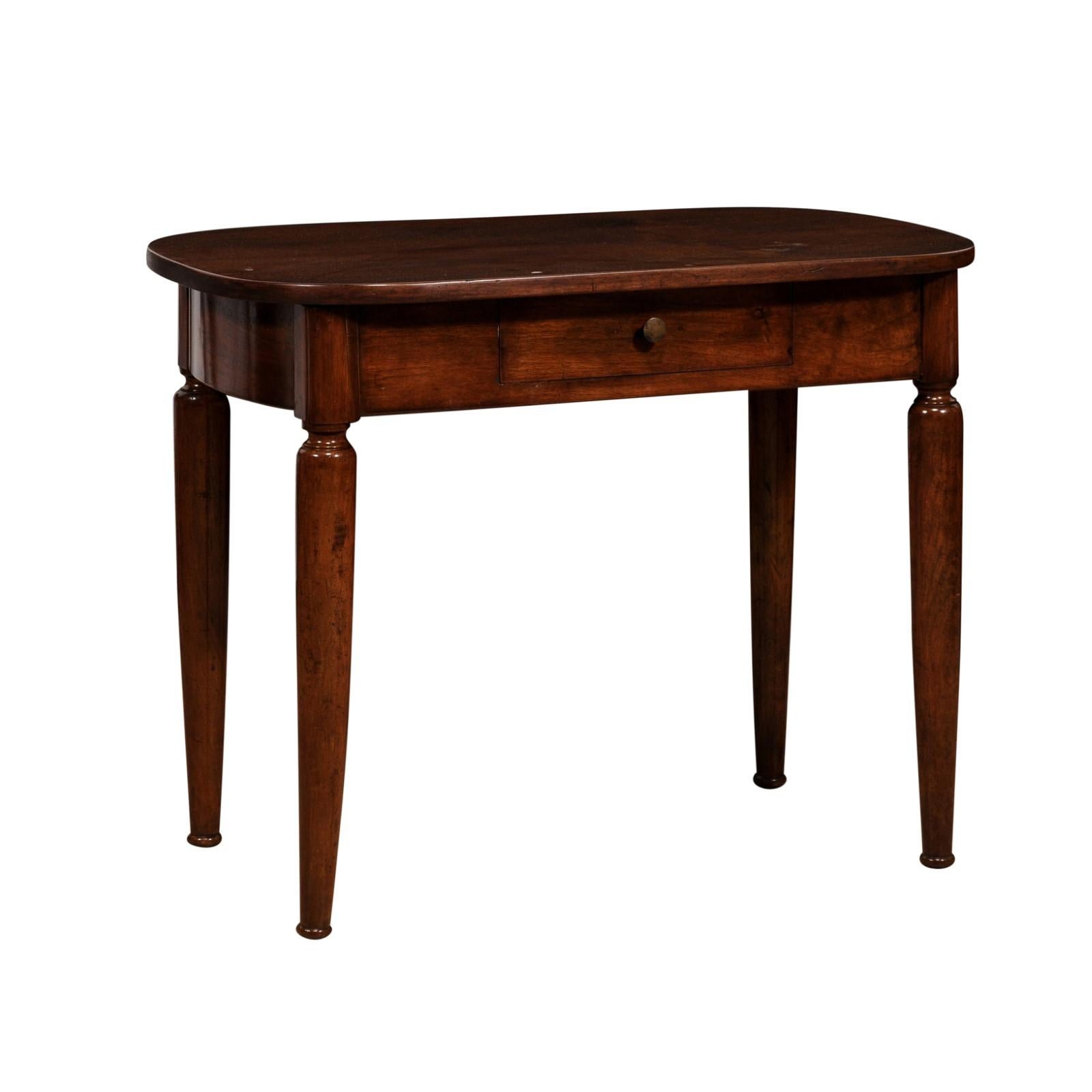 An Italian walnut side table from circa 1890 with oval top, single drawer and cylindrical tapering legs. This Italian walnut side table, dating back to approximately 1890, exudes timeless elegance and craftsmanship. Its oval top showcases the