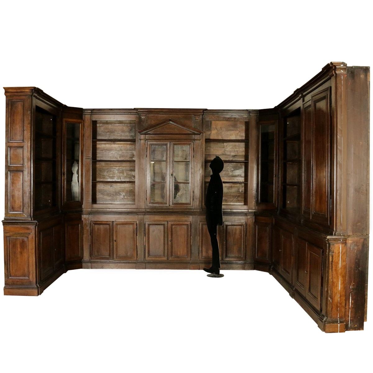 A good late 18th century Italian Neoclassical library room panneling. This room consists of one central bookcase with a tympan centerpiece. At both sides angle cabinets with hand blown glass are integrated. They are followed at both angles with an