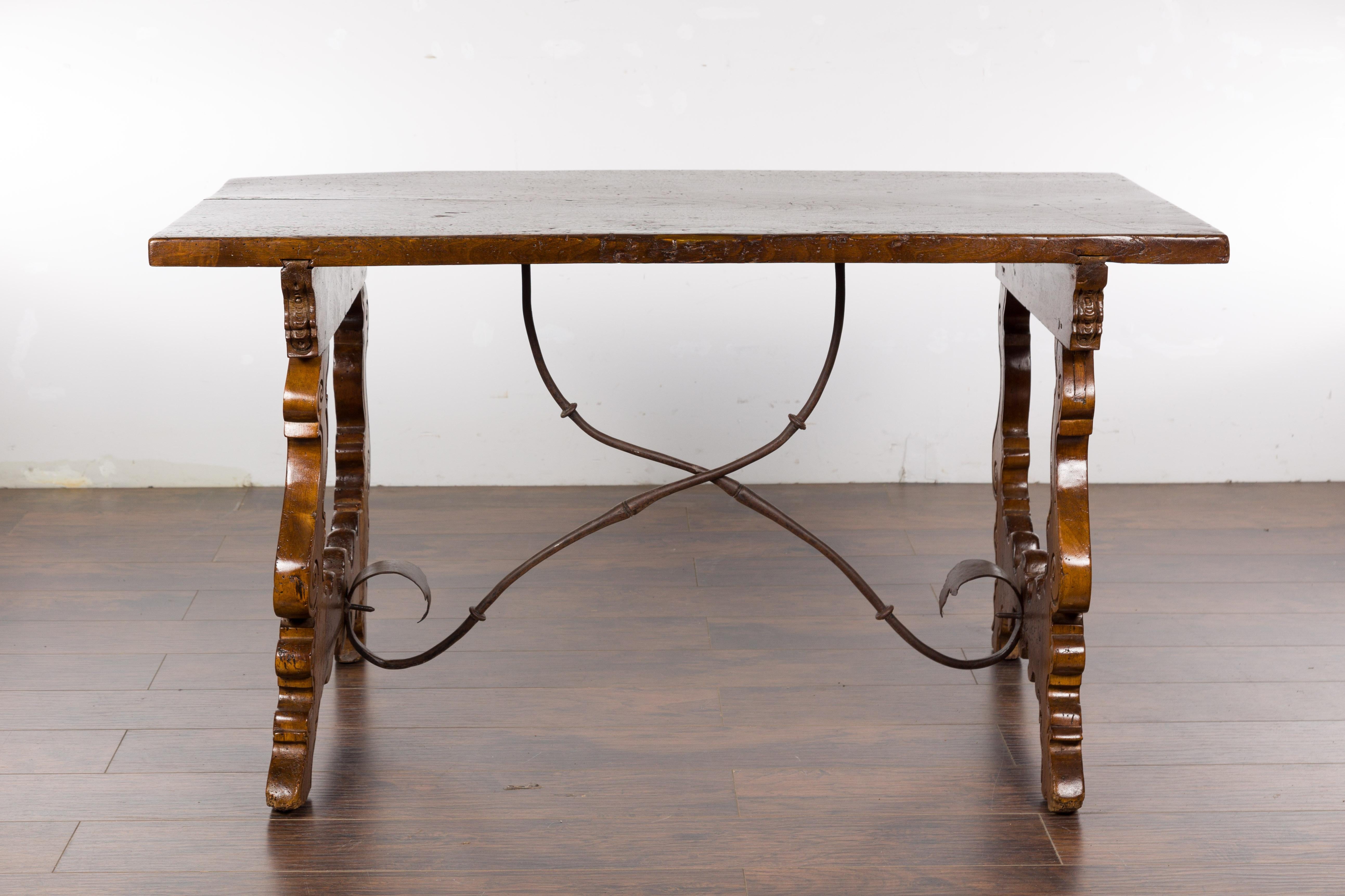 An Italian Baroque style walnut Fratino console table from the 19th century with carved lyre shaped legs and iron stretchers. Add a touch of opulence to your home with this stunning Italian Baroque style console table from the 19th century. Crafted