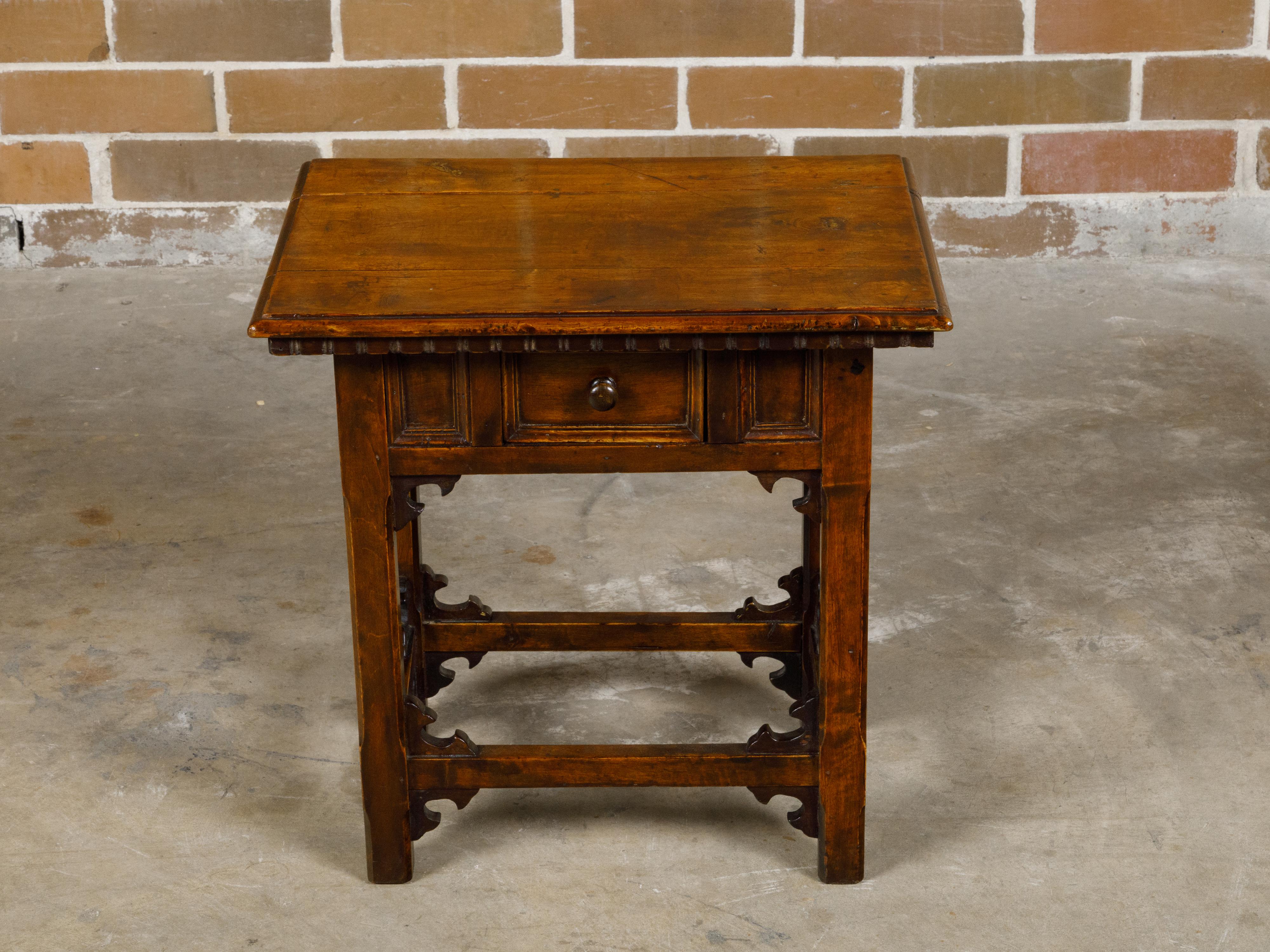An Italian walnut side table from the 19th century with single drawer and carved spandrels. This Italian walnut side table, hailing from the 19th century, showcases the timeless elegance of traditional craftsmanship. The table features a rectangular