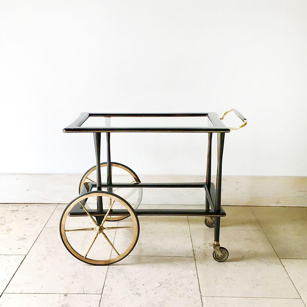 Italian polished walnut framed two-tiered barcart on large brass wheels and castors with inset glass shelves. 
The handle is a mix of brass and walnut, 1960s.