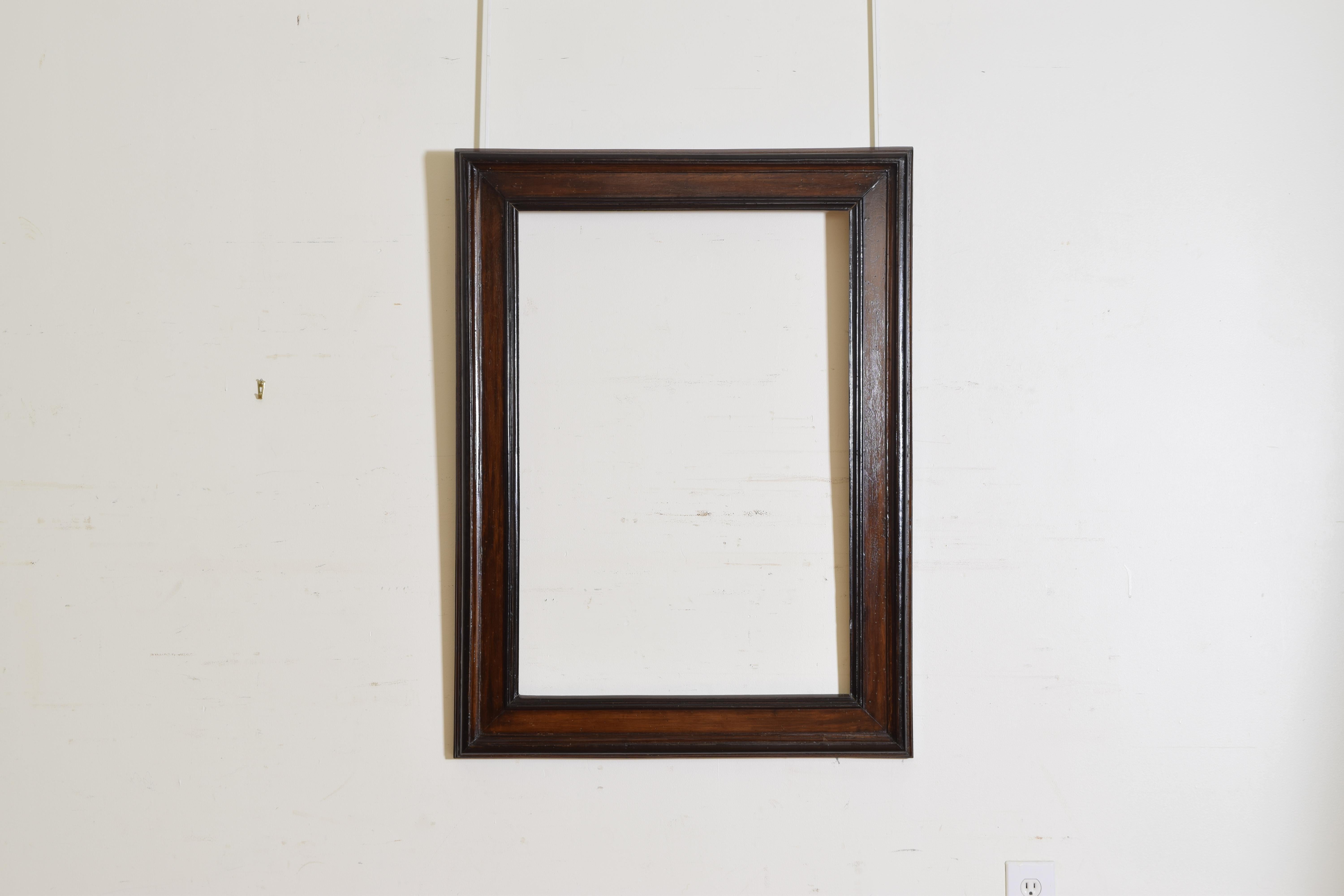 The rectangular frame or mirror with walnut veneer and raised ebonized moldings.