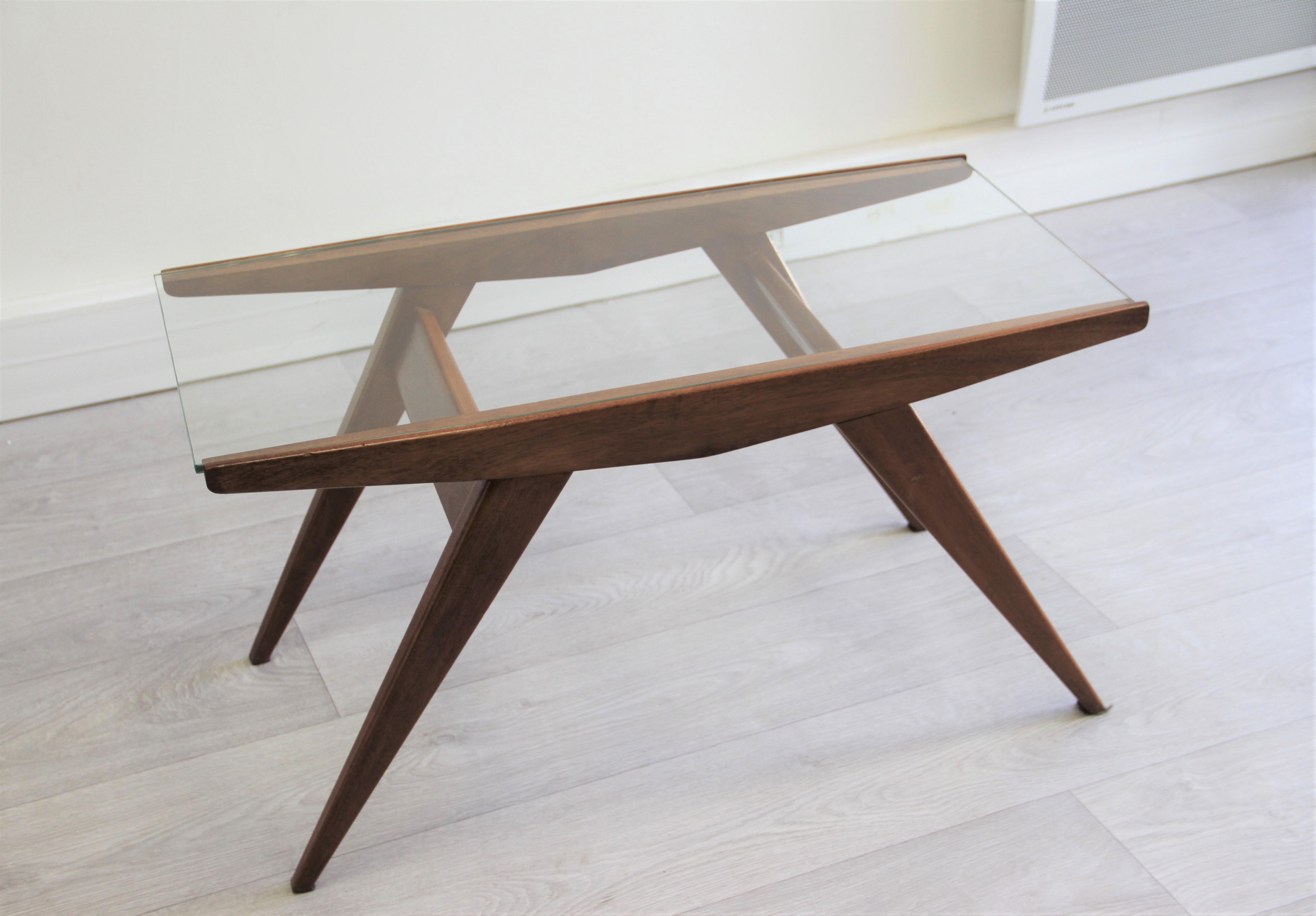 The rectangular glass top rests on a walnut structure, with angled supports, Italian, 1950s.