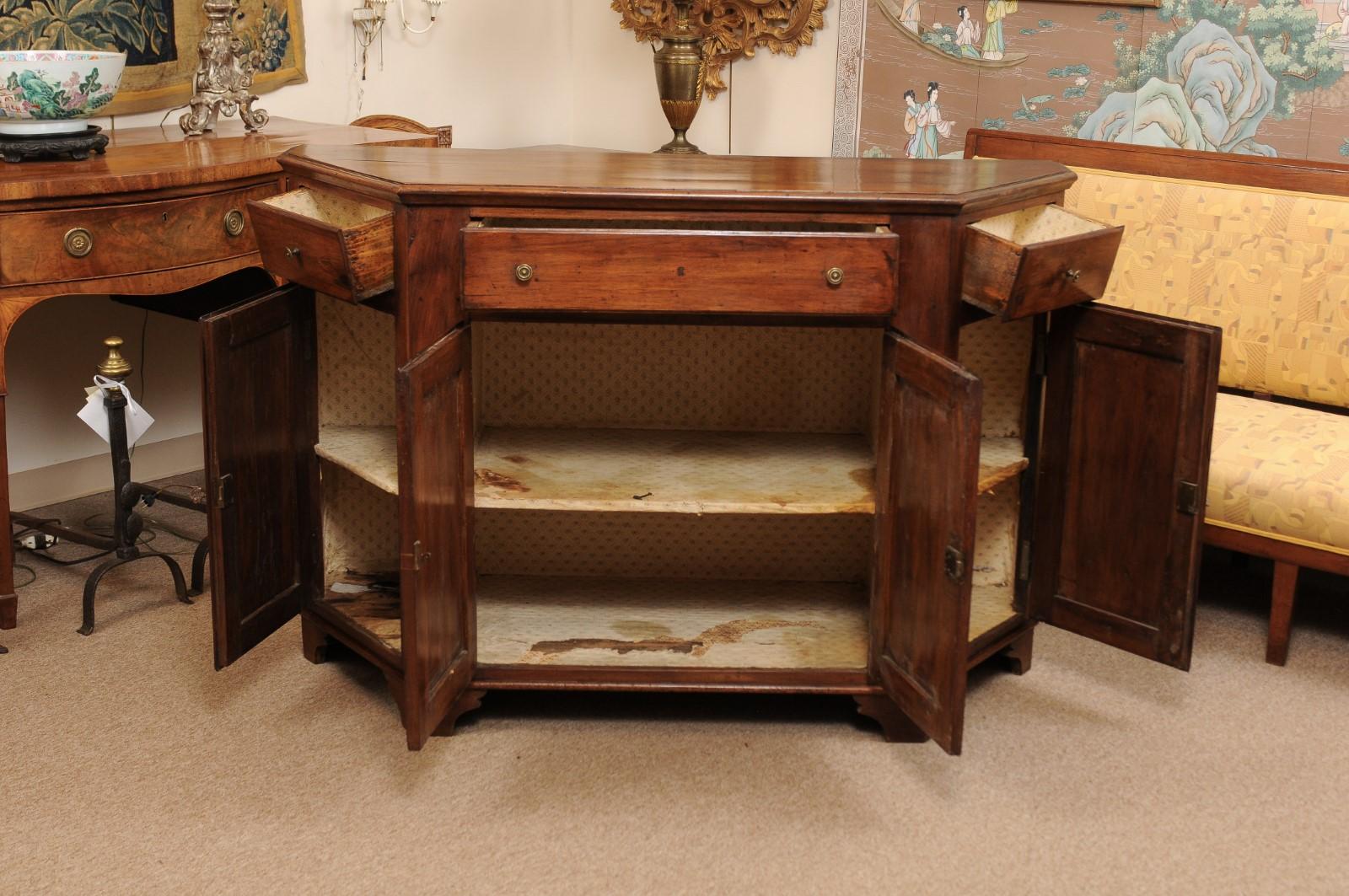 An early 19th Century Italian Walnut Credenza with Canted Sides, 3 drawers & 4 Cabinets below ending in bracket feet. 
