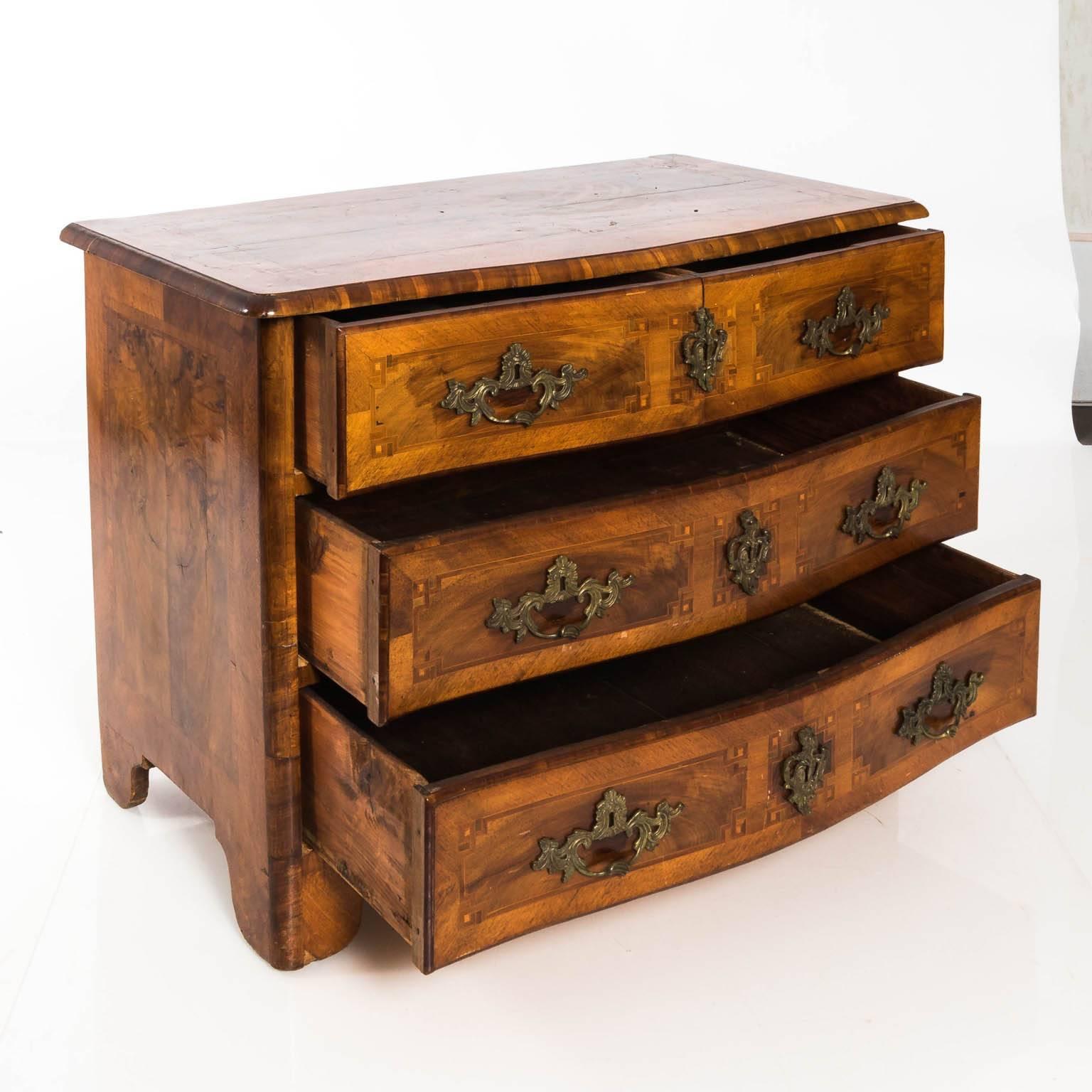 Italian walnut three drawer chest that featured a serpentine front, brass foliage escutcheon, and Greek key inlay, circa 19th century.
 
