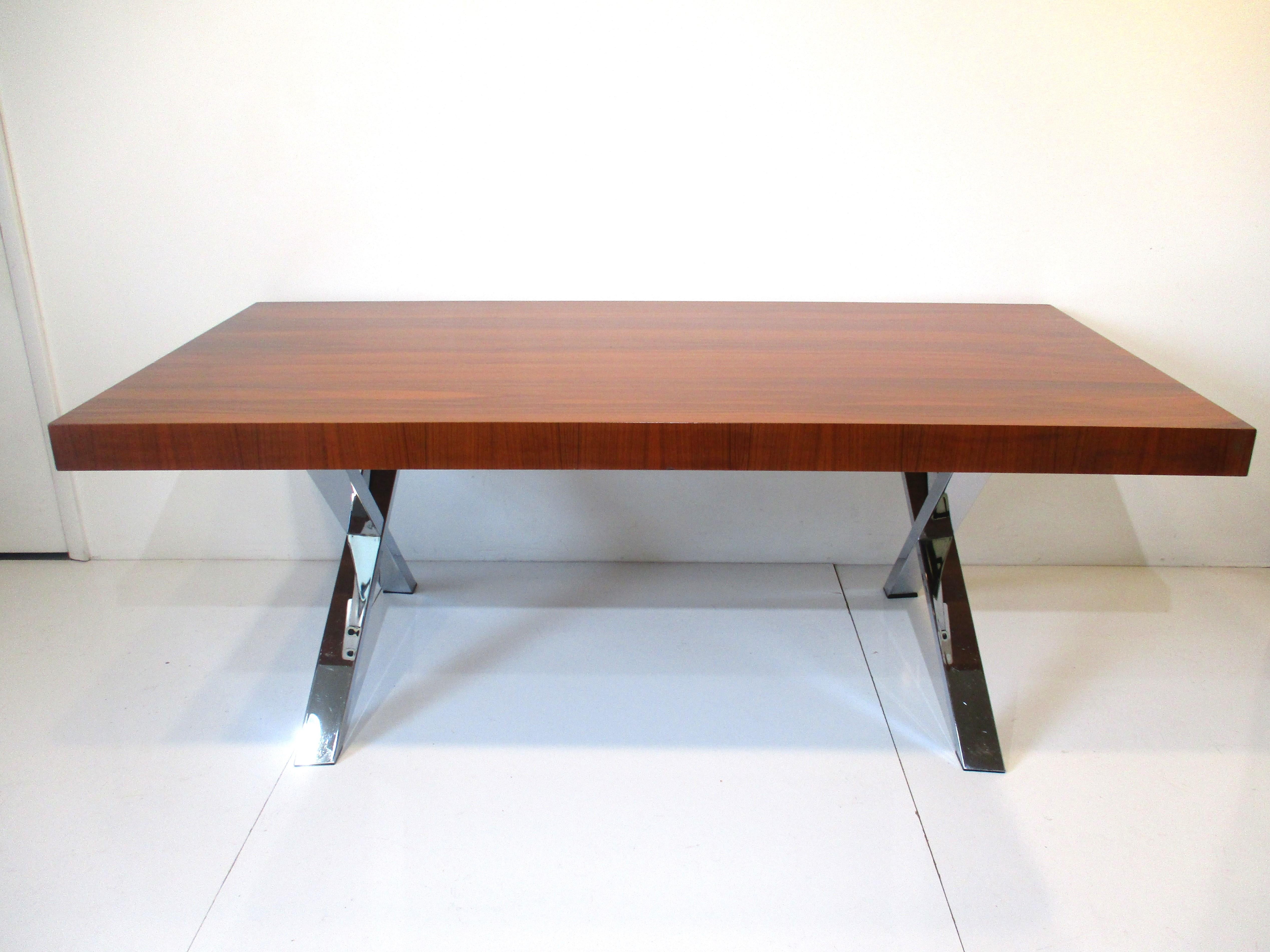 A well made walnut slab styled dining table with chromed metal X base design giving the piece a presence. Made in Italy this piece has a simple but elegant look that would work in many interiors.