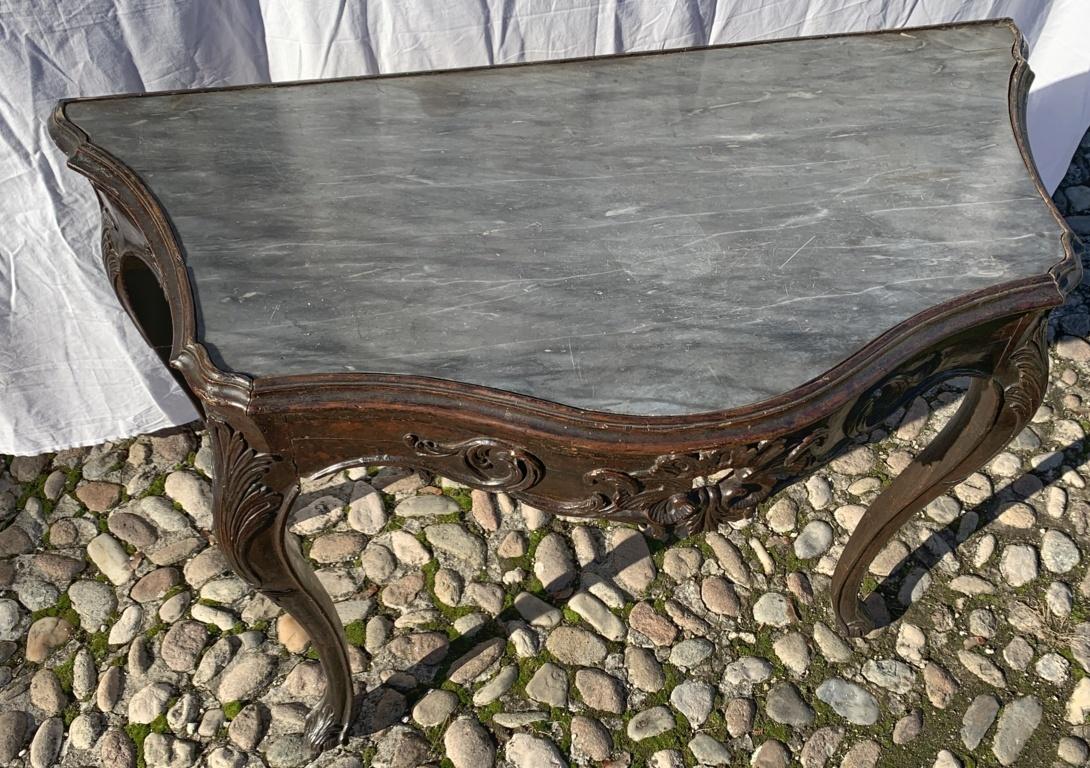 Entirely in walnut wood finely carved with floral motifs and openwork, elegant curly feet and shaped top with coeval gray marble.
