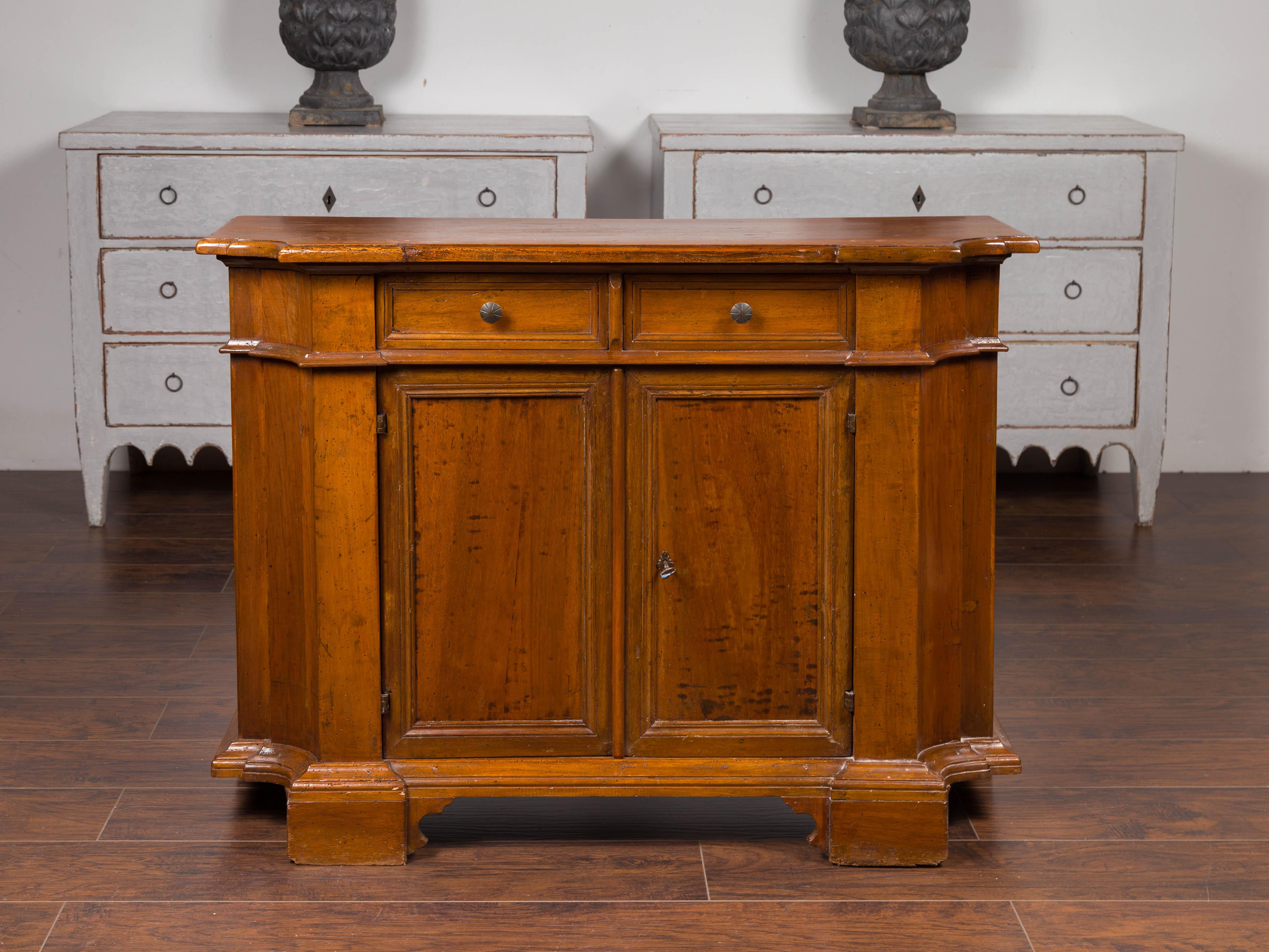 An Italian walnut credenza from the mid-19th century, with two drawers over two doors, bracket feet and curving sides. Born in Italy during the third quarter of the 19th century, this walnut credenza features a single plank top with rounded edges,