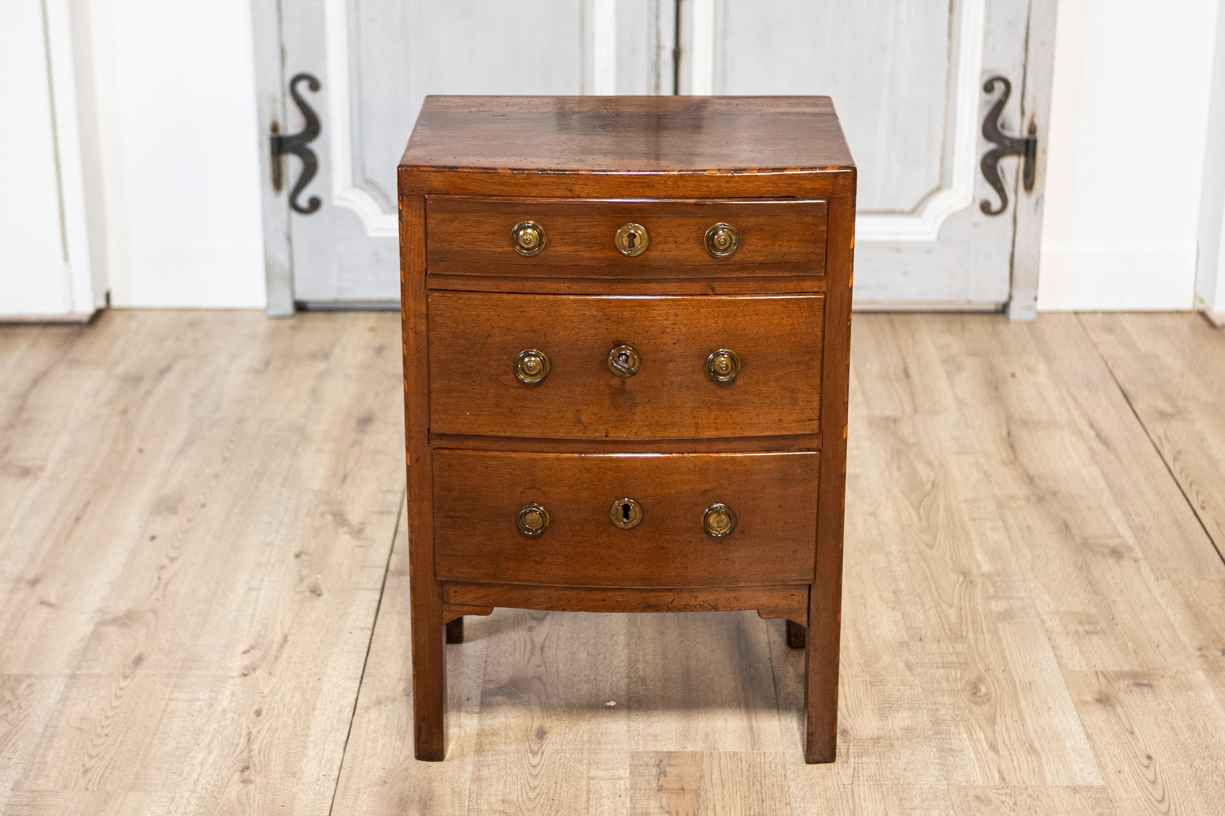 An Italian early 19th century walnut three-drawer bedside chest from Vicenza with, inlaid banding and Classical brass hardware. This early 19th-century Italian walnut bedside chest from Vicenza epitomizes classic elegance and utility. It features a