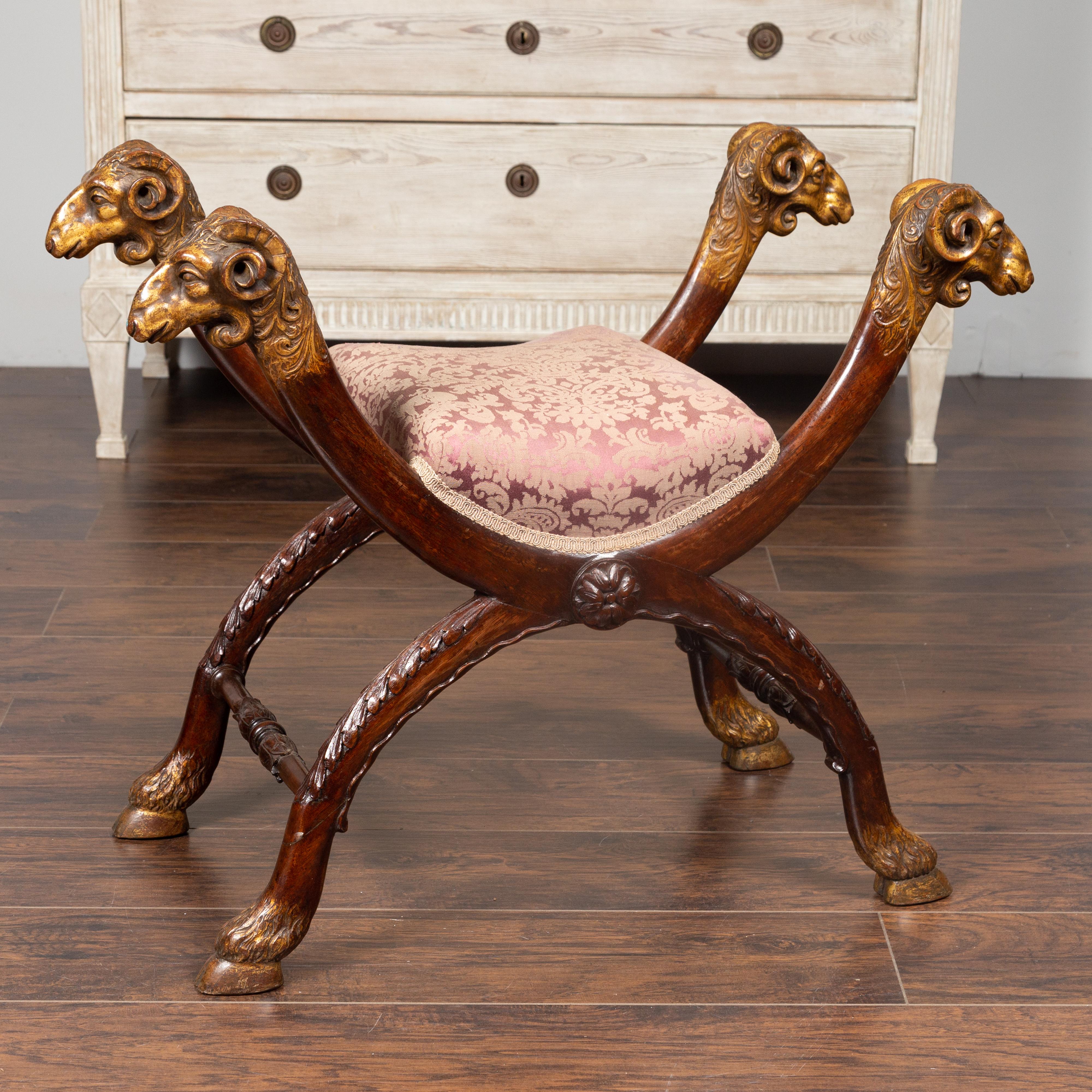 An Italian Empire style walnut curule stool from the late 19th century, with carved rams heads and X-form base. Born in Italy during the third quarter of the 19th century, this stunning Empire style curule stool features an upholstered curving seat