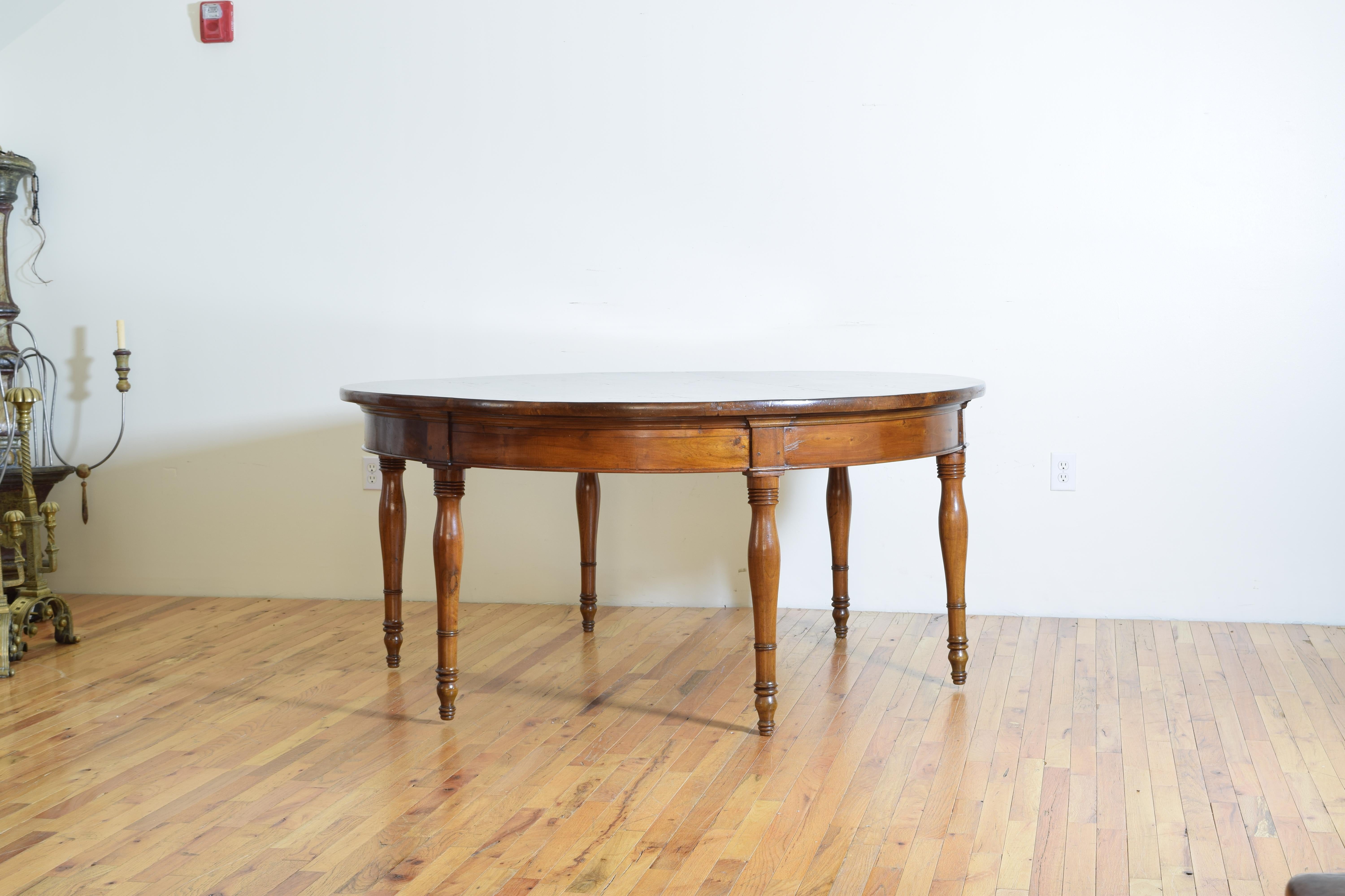 Constructed entirely of solid walnut, the circular top composed of 5 joined boards with a rounded edge, the apron with upper and molded edges and notched capitals at the joints above the legs, the legs with horizontal turnings and slightly tapering,