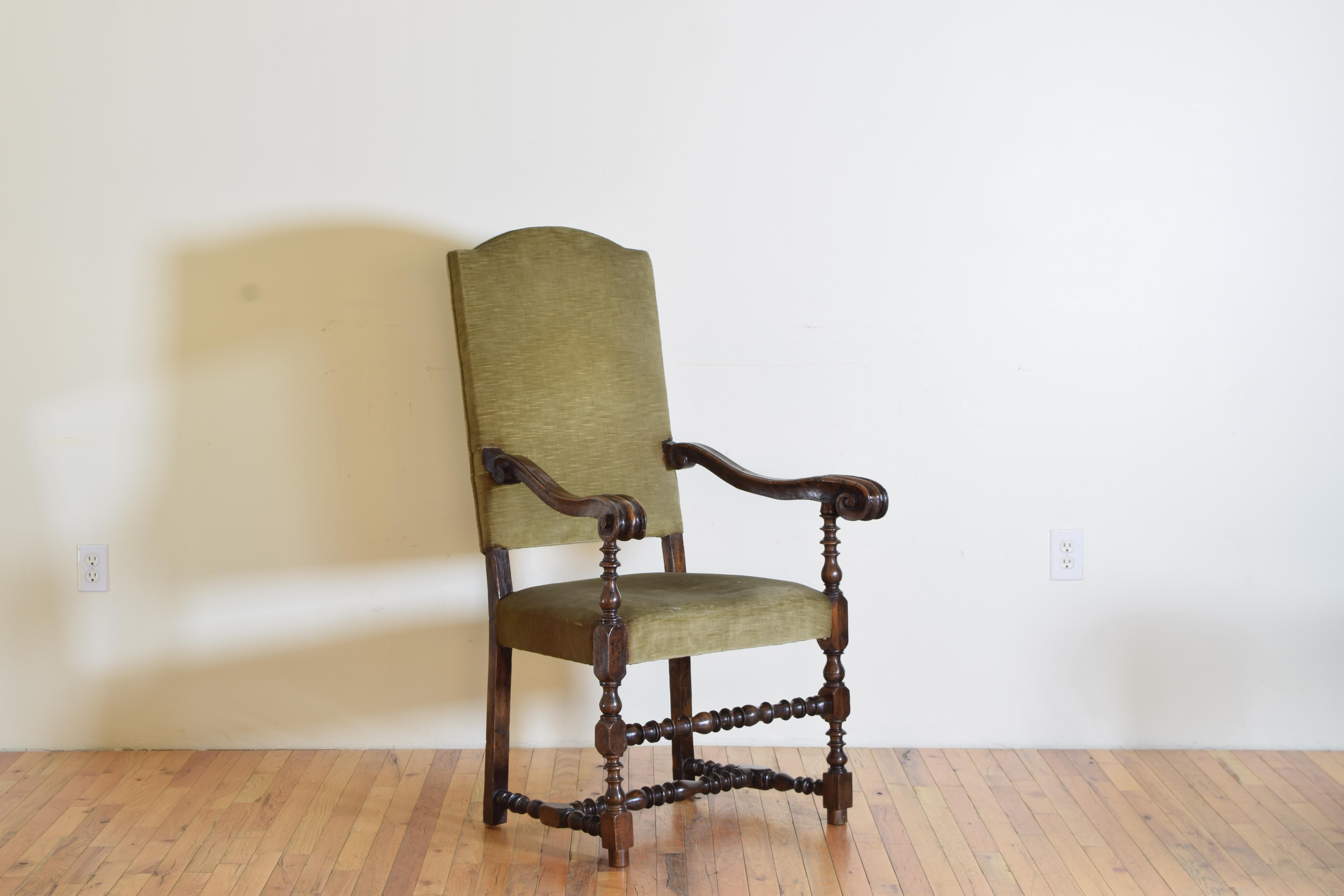 A Louis XIII Period Walnut and Upholstered high curved back armchair with a turned stretcher on the front and at the base. Having large and well-patinated snail-shaped carved hand rests.