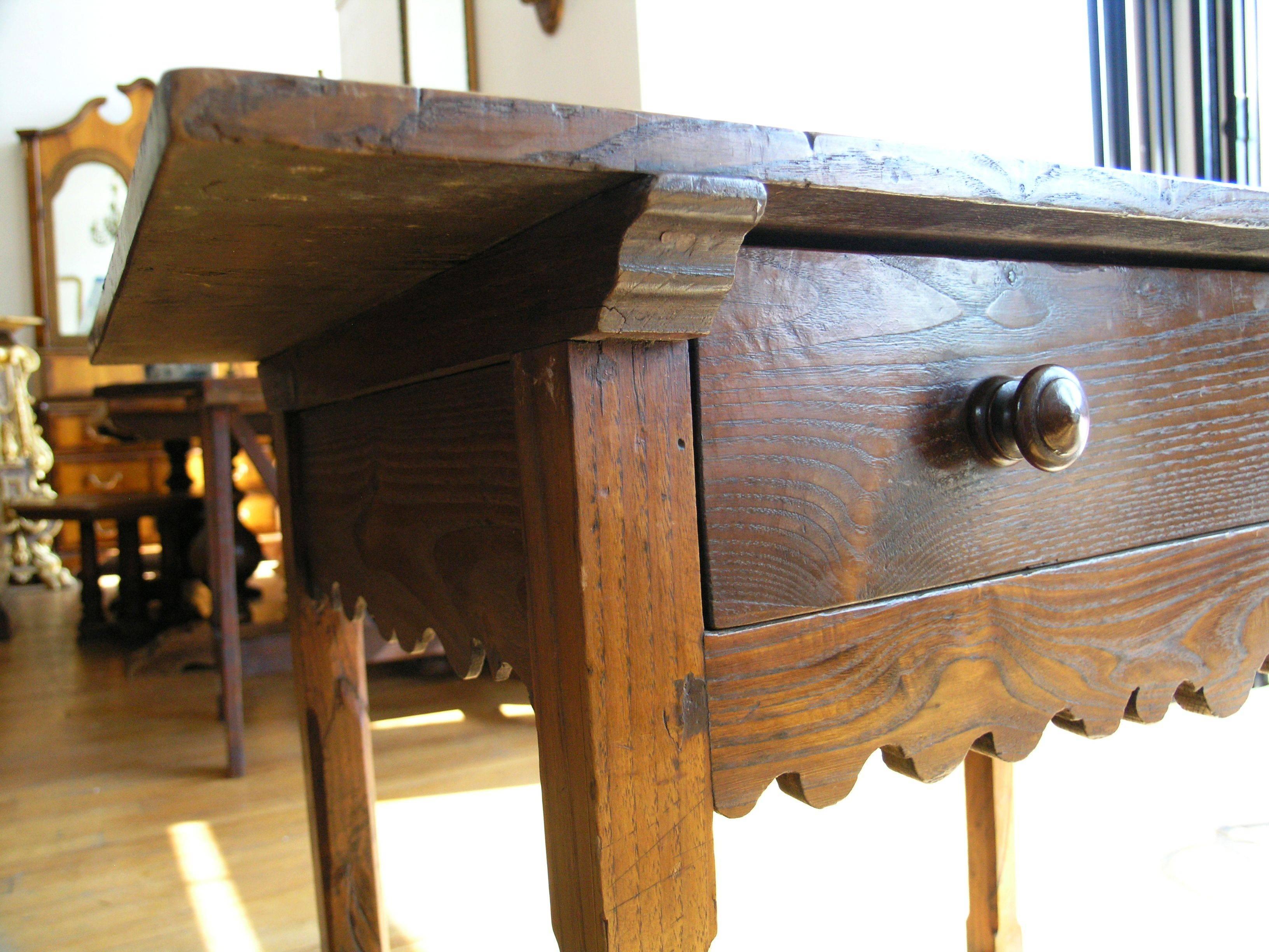 The rectangular top above a long drawer and a frieze with scalloped edge raised on chamfered legs joined stretchers.