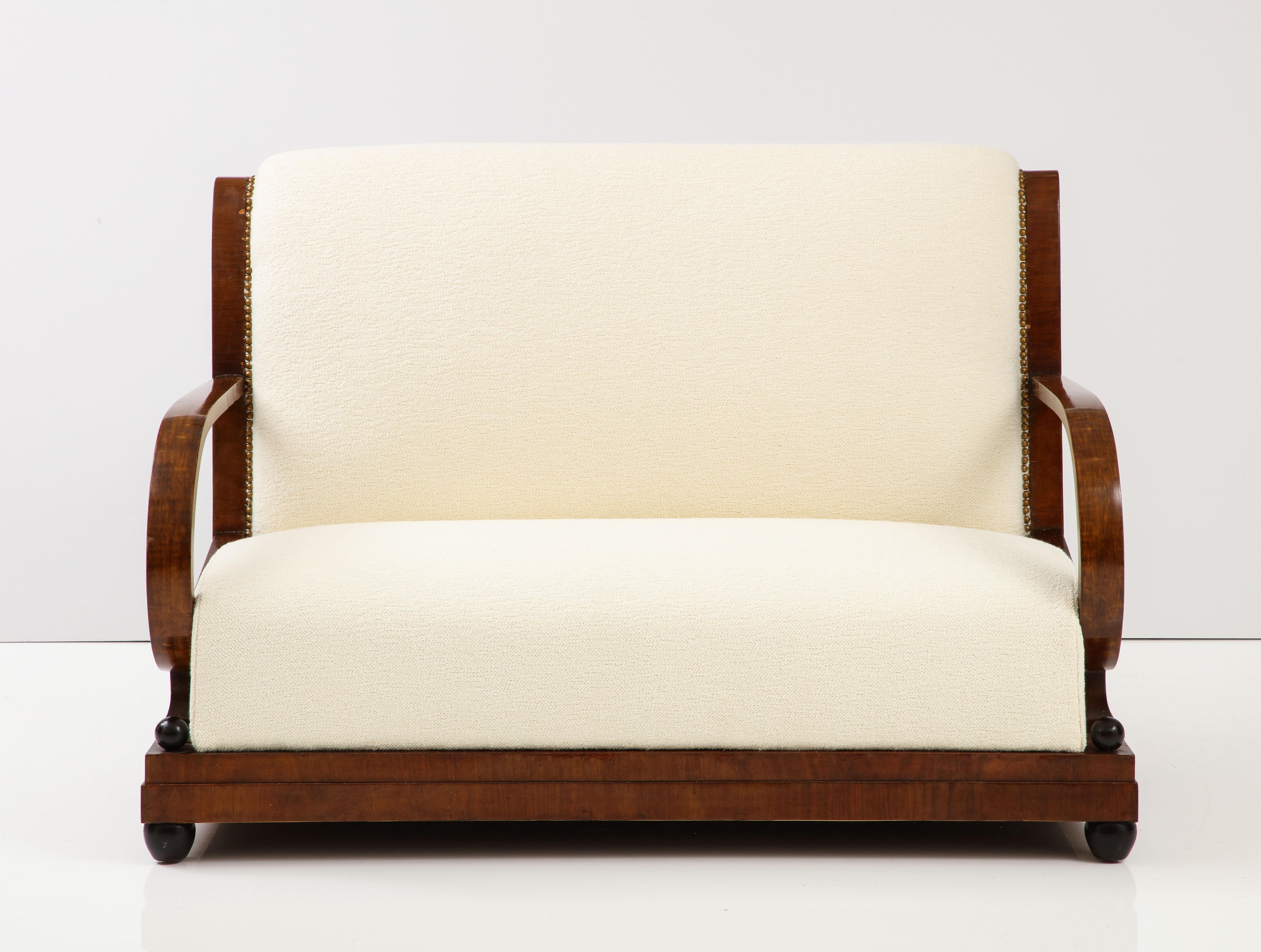 Ein italienisches Sofa aus den 1920er Jahren aus der frühen Art-déco-Zeit in Norditalien. Das reiche Nussbaumholz ist fein geschnitzt und unterstreicht die natürliche Schönheit des Holzes. Die Rückenlehne des Sofas ist anmutig geschwungen und