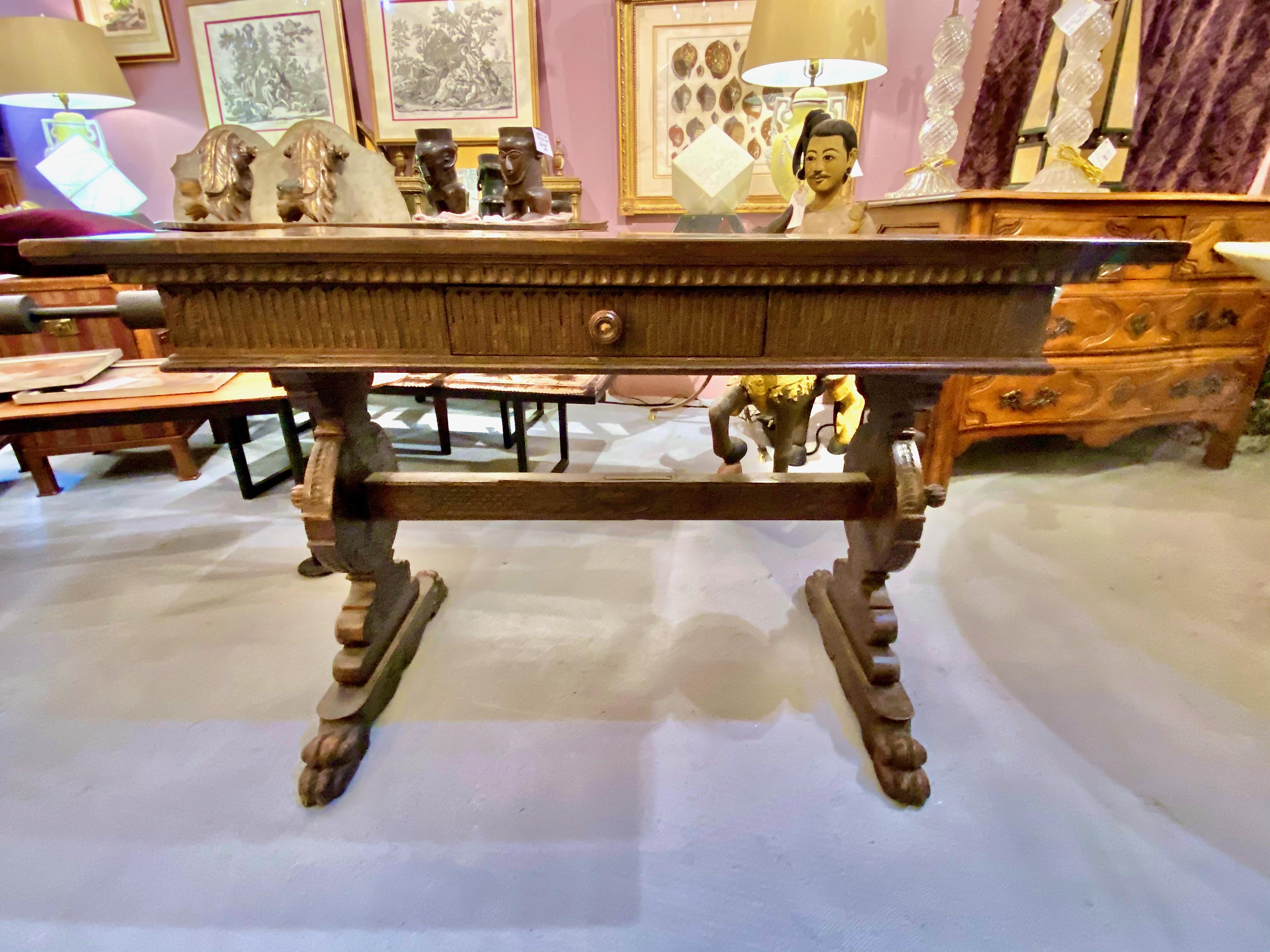 This is a charming rustic Italian (probably Tuscan) 18th century side or writing table. The table features a chip-carved apron with a single drawer supported by carved lion's paw feet and a central stretcher. The walnut top is a later marriage, but
