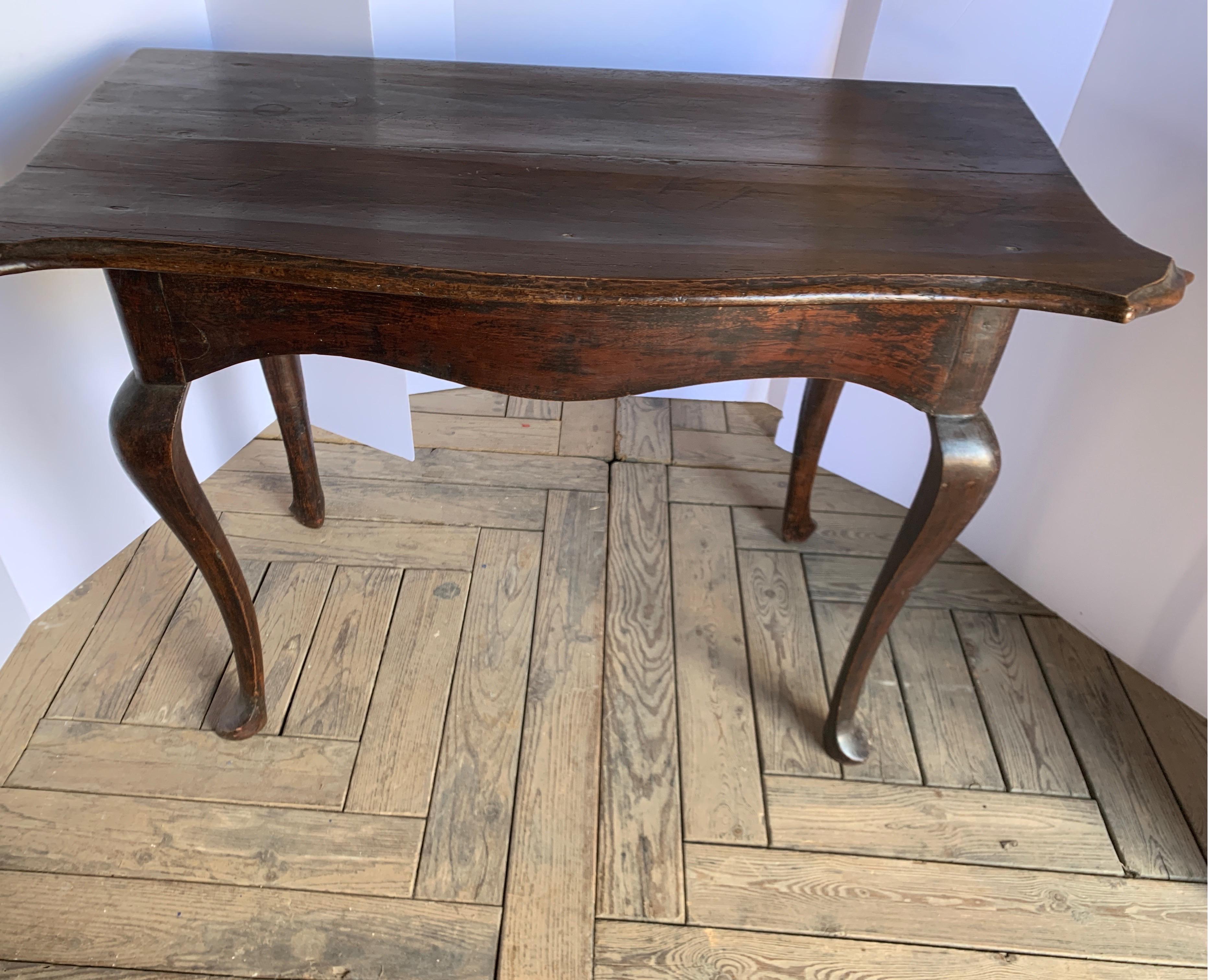 This is an elegant shaped walnut demilune shaped table from Italy. It dark warm patina gives it added character. It's one of a pair sold separately. It is pegged and beautifully constructed. The front leg on the left has had a repair in the past. It
