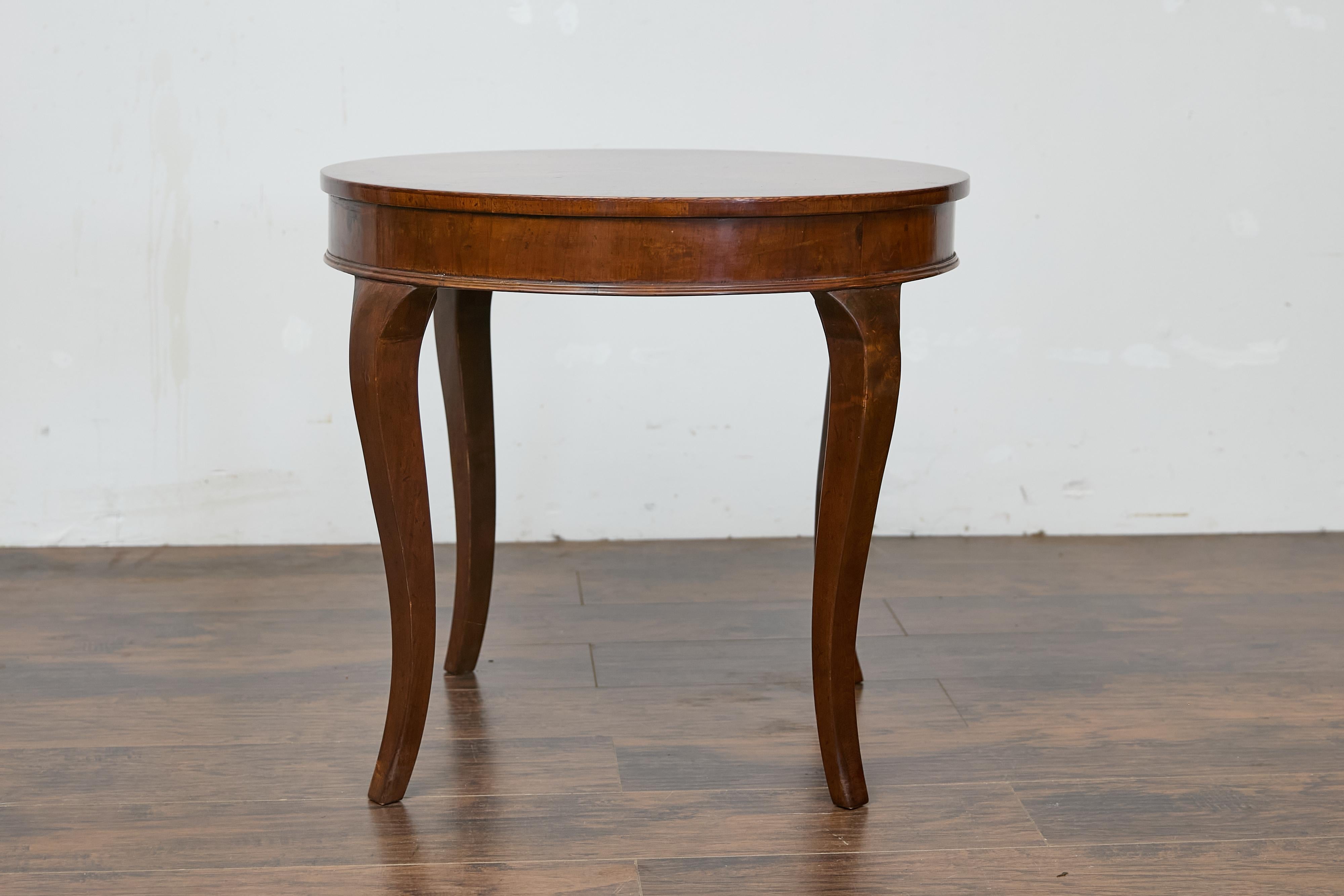 Ein runder Tisch aus italienischem Nussbaumholz mit Cabriole-Beinen. Dieser runde Tisch aus italienischem Nussbaumholz besticht durch seine raffinierte Schlichtheit und sein elegantes Design. Die Tischplatte ist mit einem schönen Viertelfurnier