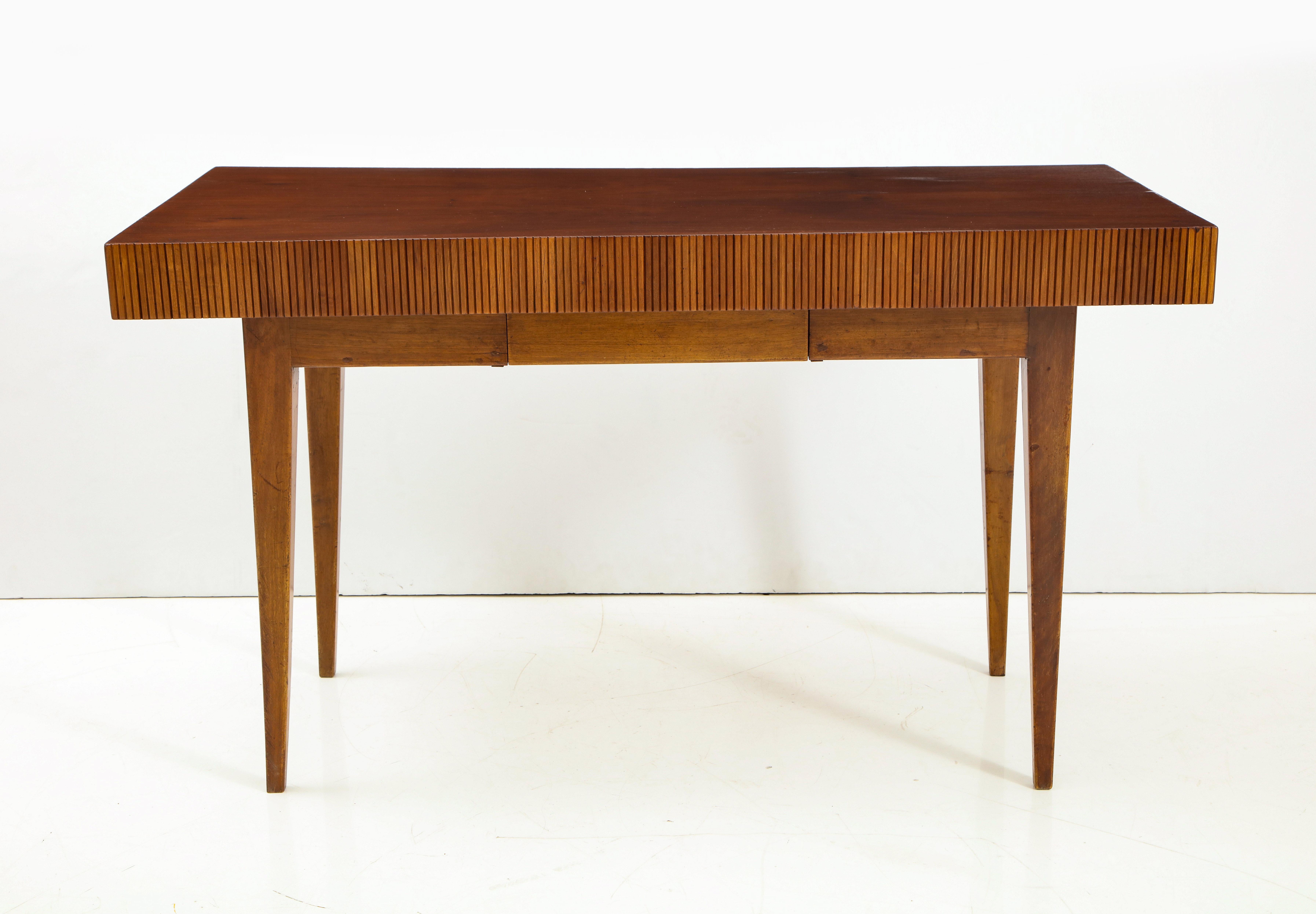 Italian walnut table or writing desk with extended floating top with a single drawer and reed carving on the apron surround, supported by elegant tapered legs.
In the Manner of Gio Ponti.
Italy, circa 1950.
Size: 31 1/2” high x 55” wide x 27 1/2”