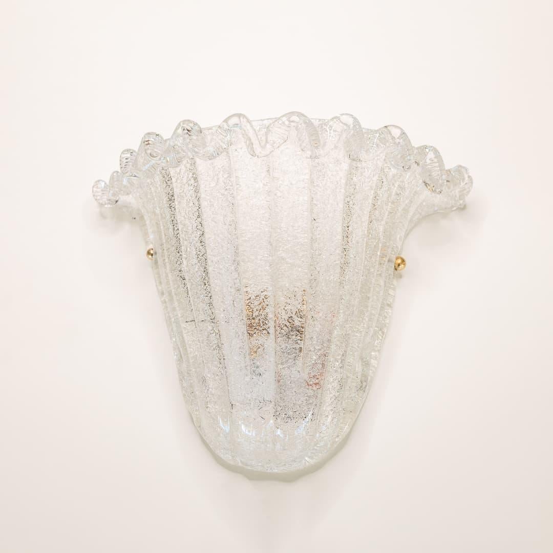 Beautiful 1960's Italian glass sconce with clear curved ribbed glass shade and wavy glass detail on top. White metal backplate with brass hardware and newly re-wired. Illuminates beautifully. Takes one E12 base bulb, 25 W or higher using LED.