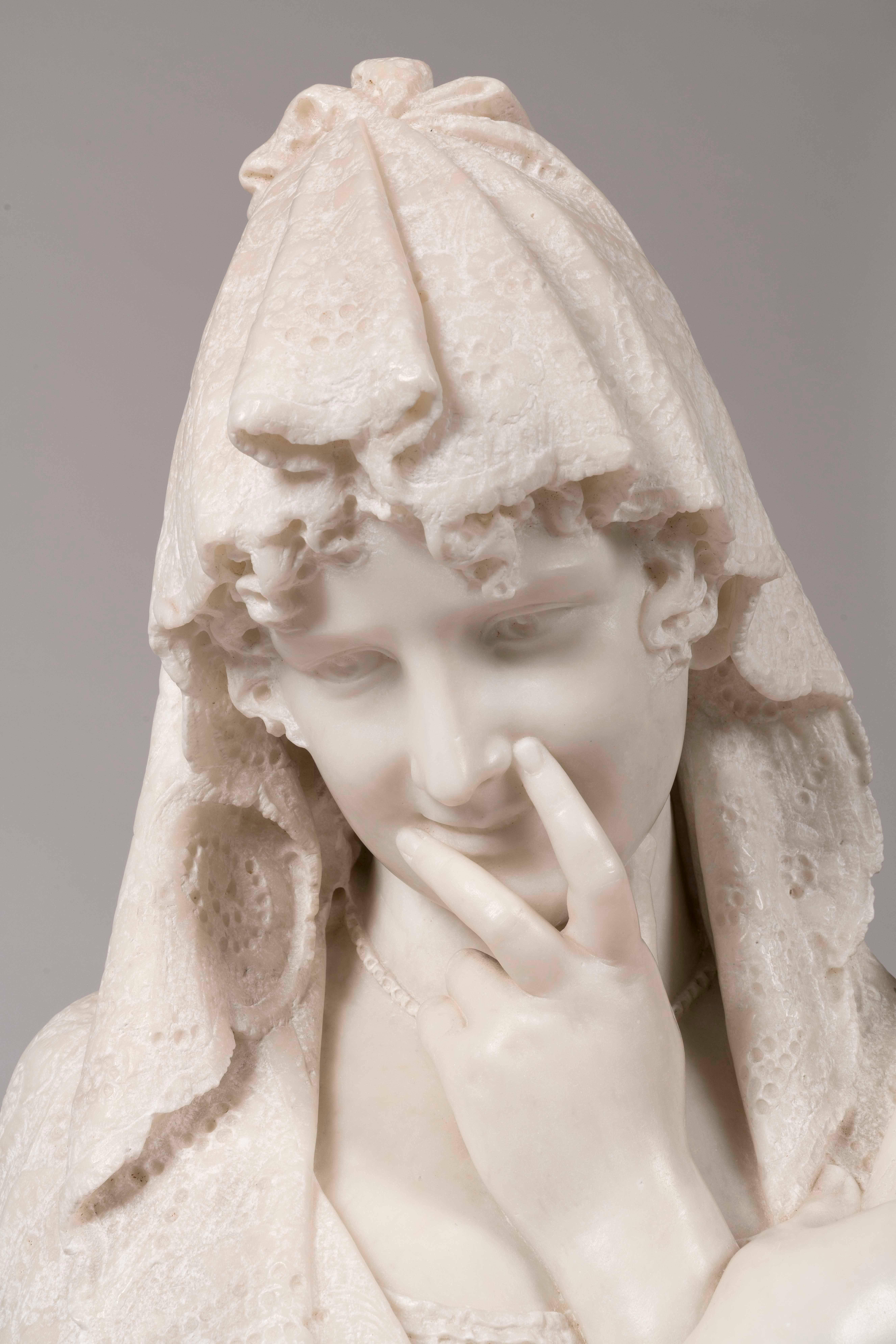 A Carrara marble bust of a shy maiden
Signed C Lapini, Firenze

Rising from a circular waisted socle, the maiden holds a fan, and coyly covers her smile with her hand; her lacework mantilla covers her head and shoulders, and is draped over the