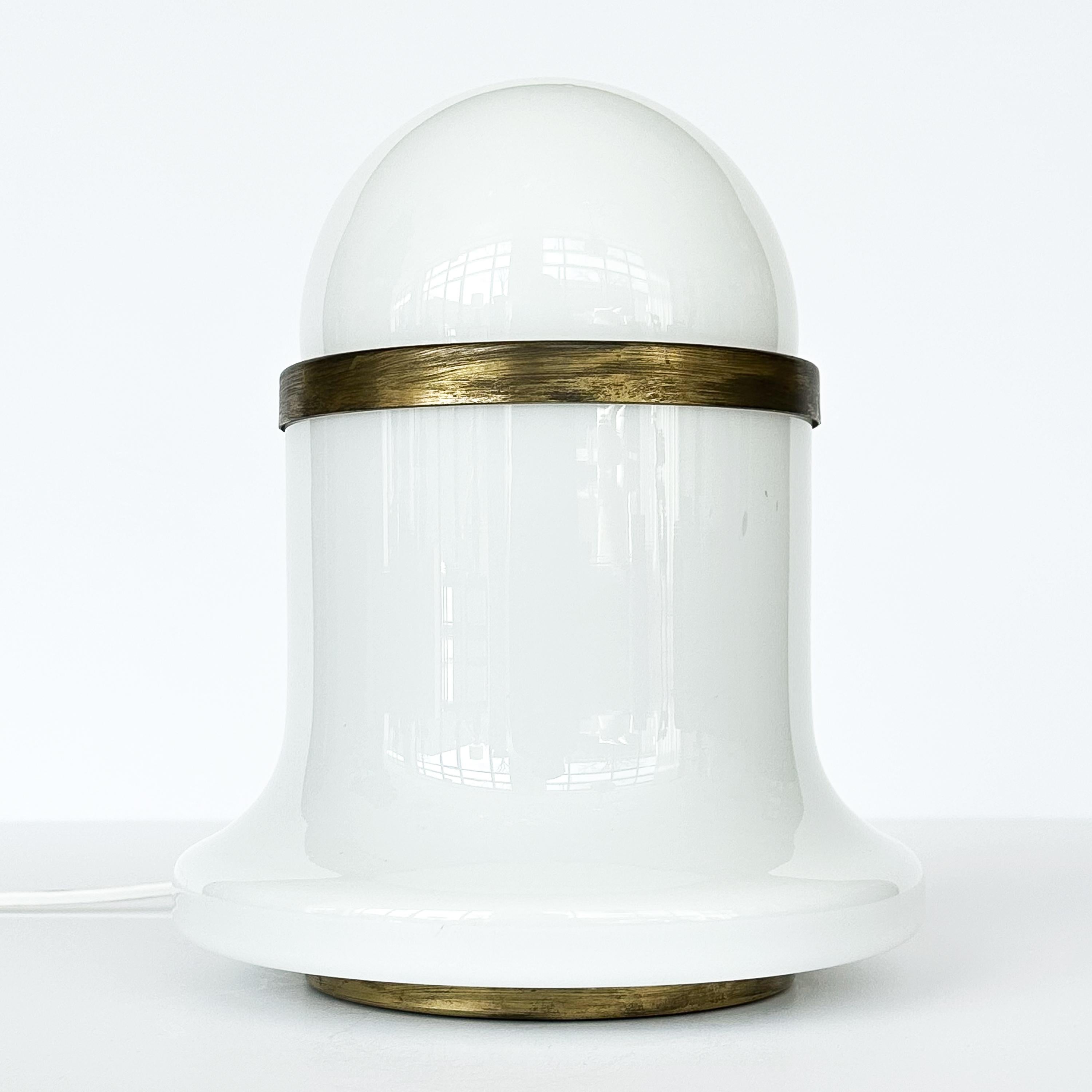 Italian white cased glass and antiqued brass table lamp, circa 1960s, designed by Goffredo Reggiani for Reggiani . This petite lamp serves as an exceptional choice for accent lighting, seamlessly blending form and function. Featuring a sweeping