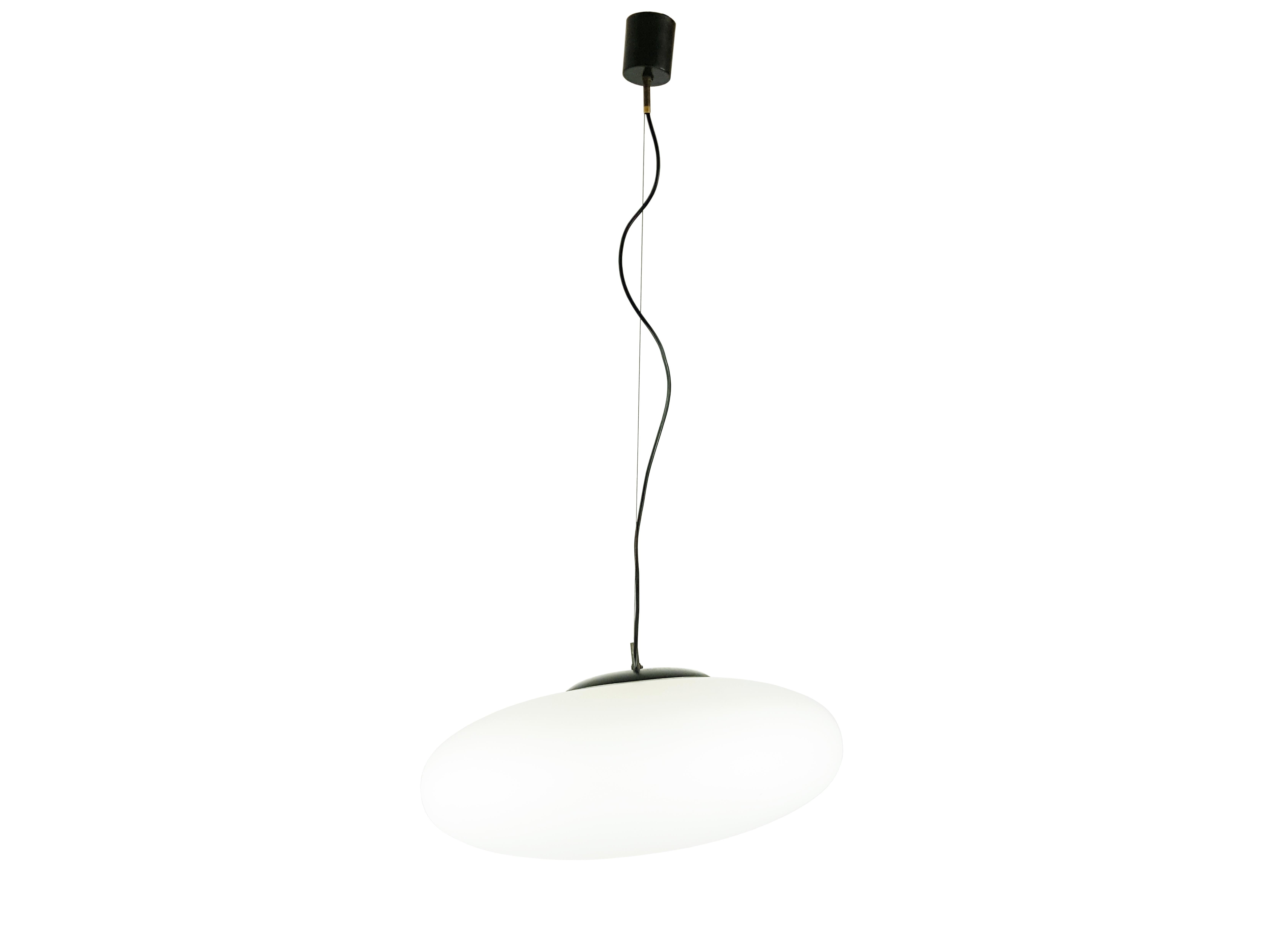 This Italian pendant was produced circa 1960s in the style of Stilnovo.
It is made from a white oval glass sandblasted shade with black metal and brass ceiling and cover. the lamp is equipped with one light socket (E27 standard) and remains in very