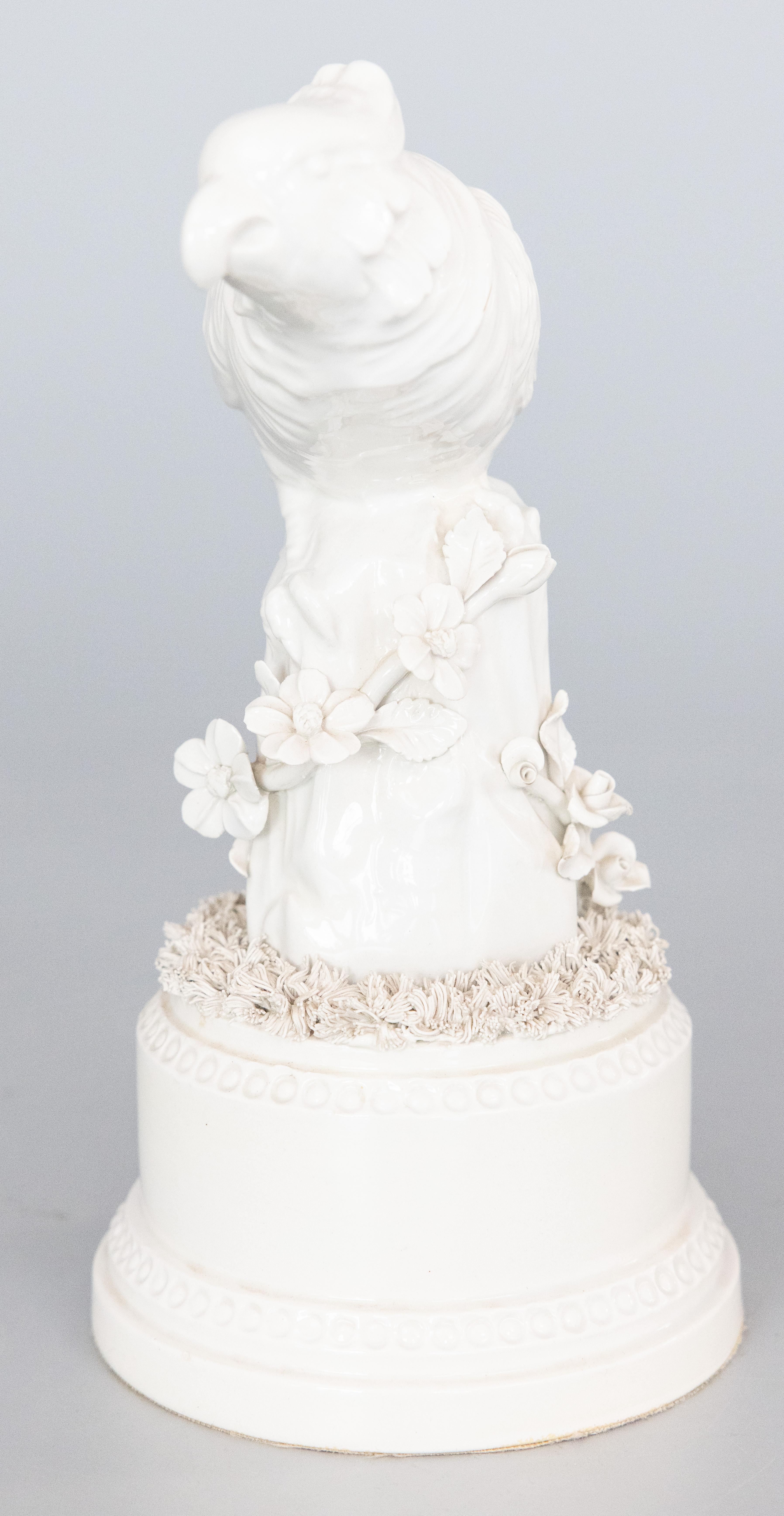 A lovely Mid-20th Century Italian white ceramic blanc de chine creamware parrot cockatiel bird sculpture figurine perched on a tree trunk pedestal adorned with flowers. Marked 