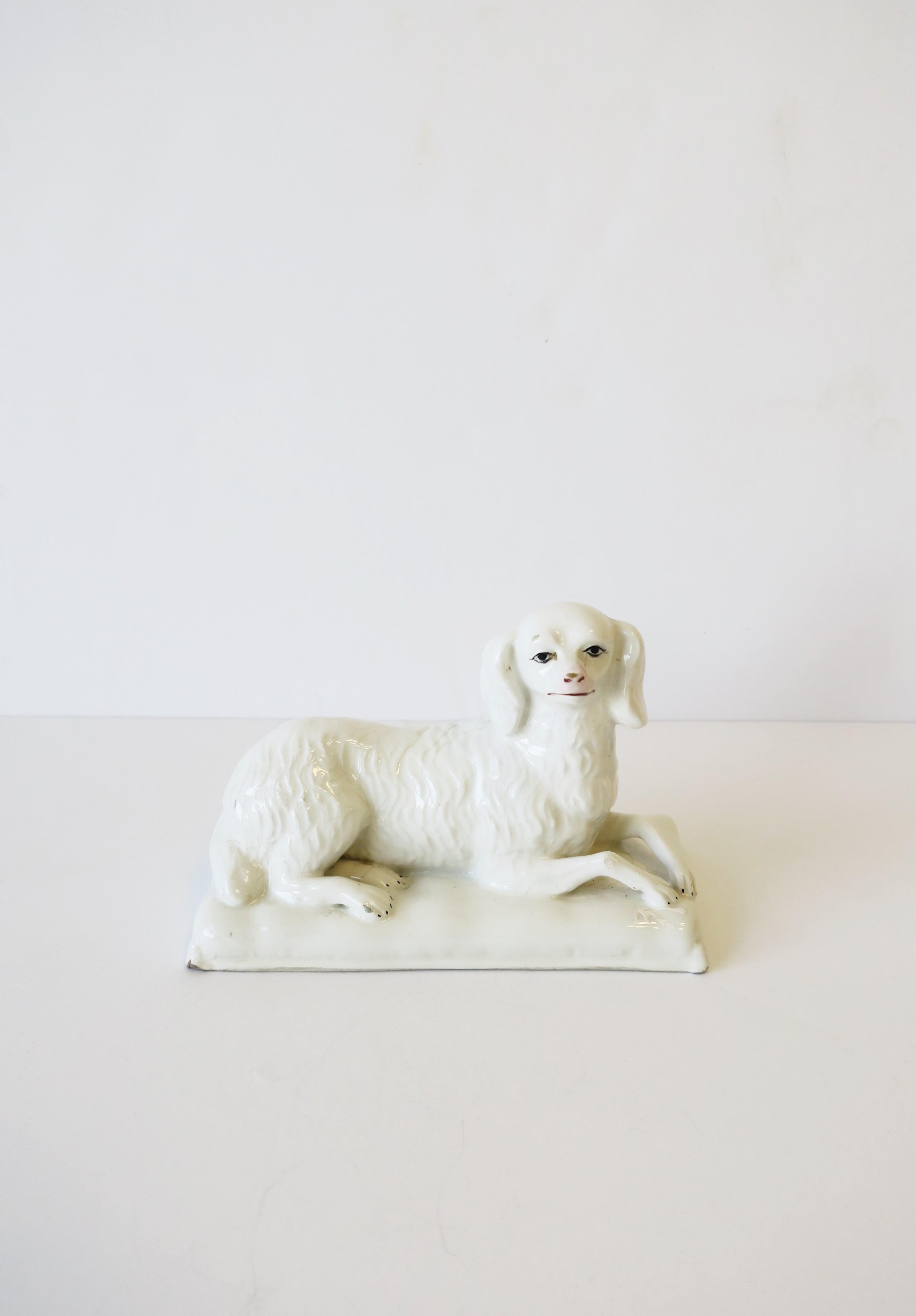 A mid-20th century Italian white porcelain decorative dog sculpture seated on a pillow, marked 