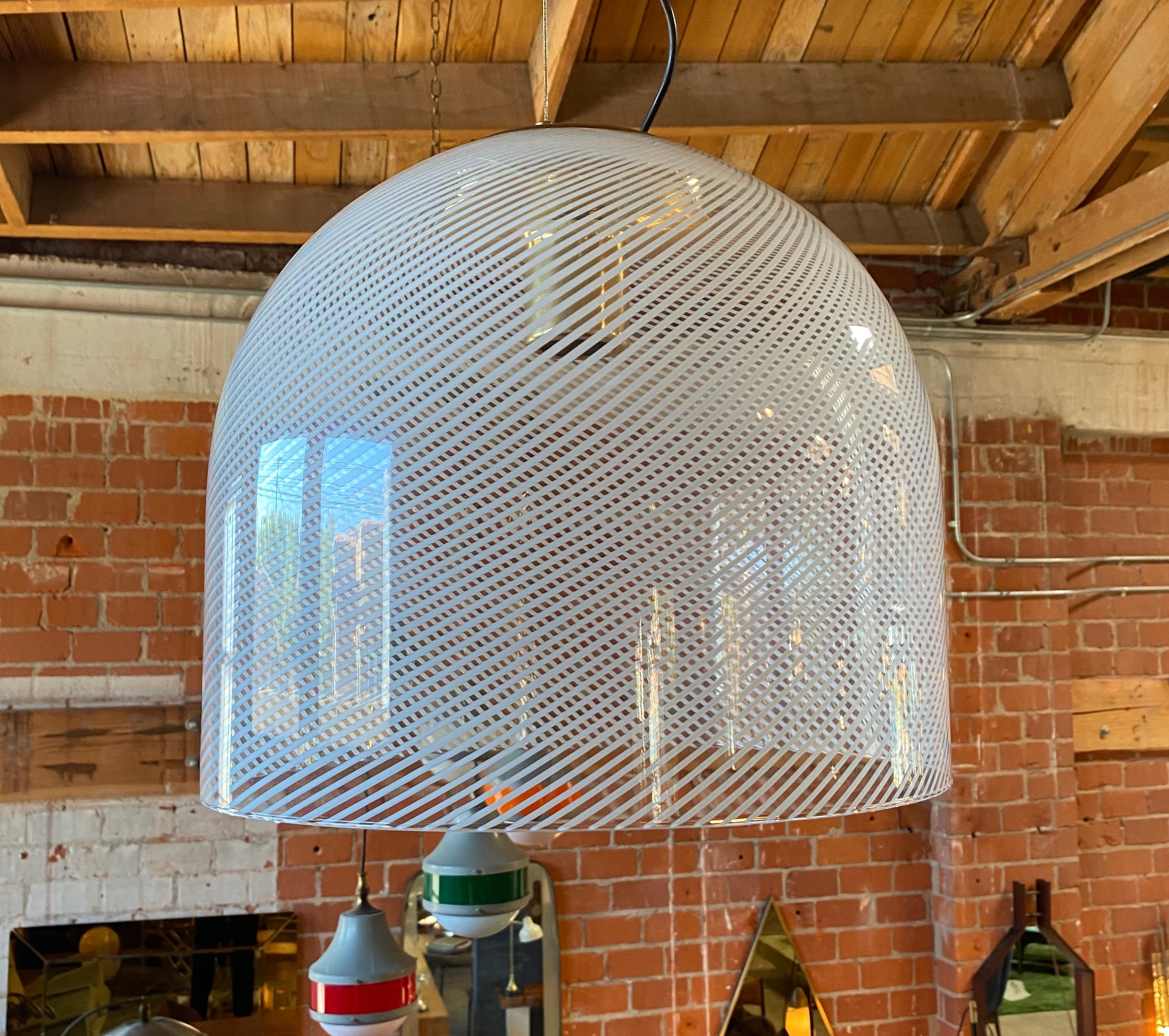 Luminaire suspendu à globe en verre avec bande étroite à rayures blanches par Mazzega, vers les années 1970. Verre de Murano en forme de sphère avec fond inversé et douille encastrée.

Ce type de lustres a été fabriqué pendant de nombreuses années