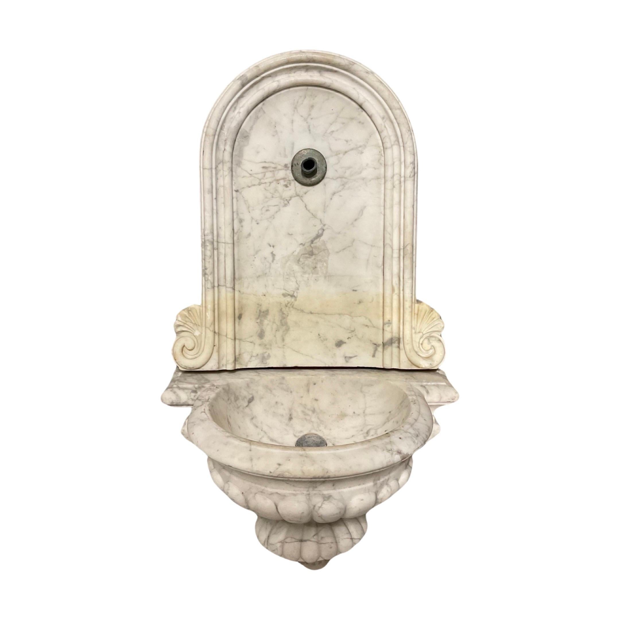 Enhance your space with a touch of elegance with our Italian White Veined Carrara Marble Wall Fountain. Handcrafted from the 18th century, this small wall fountain boasts luxurious white veined Carrara marble from Italy. Experience the beauty and