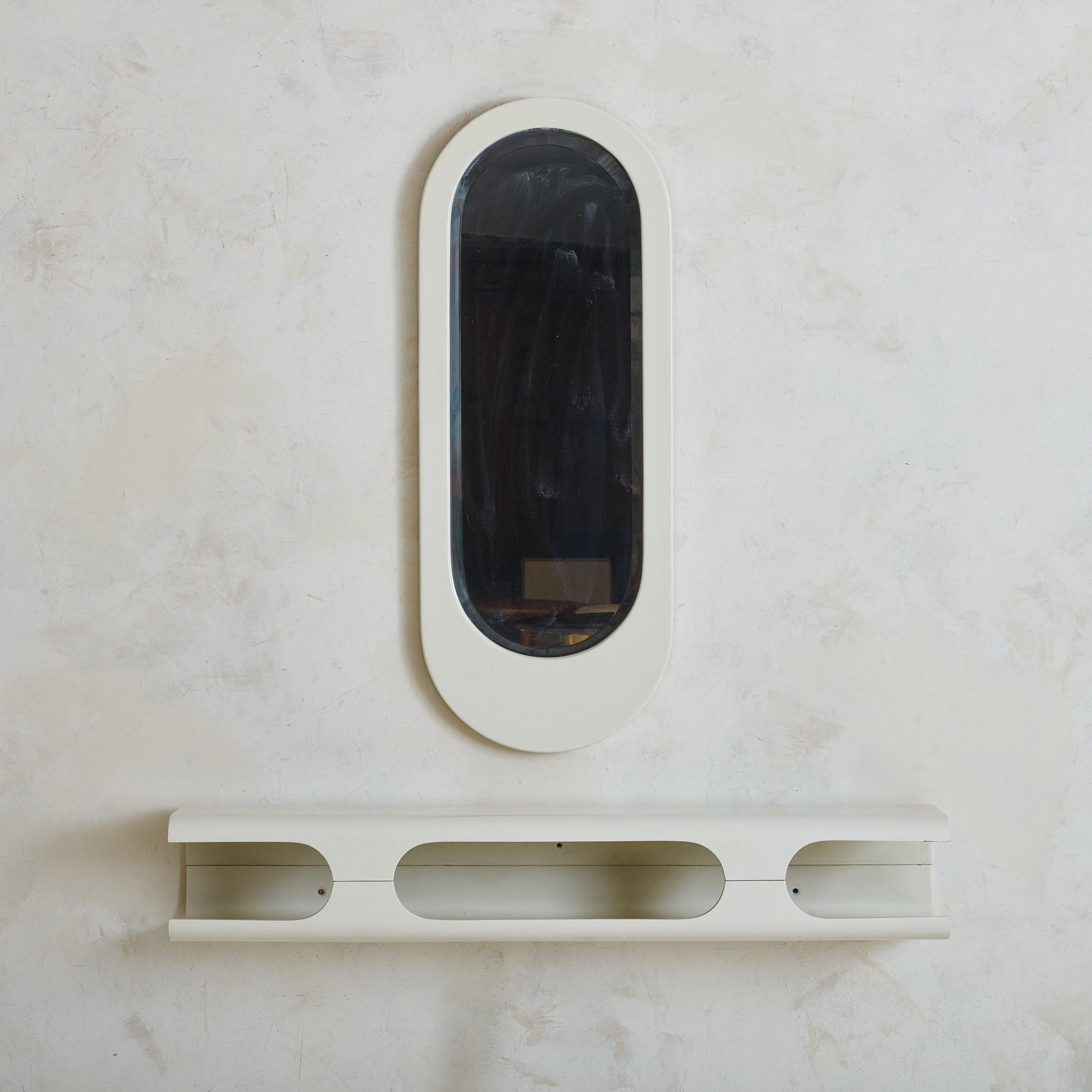 An Italian wall-mounted console and mirror set from the 1960s. Crafted from wood, each piece has a white lacquered finish. The oval mirror, encased in smooth curves, pairs seamlessly with the console's sculpted form. Three open slots offer subtle