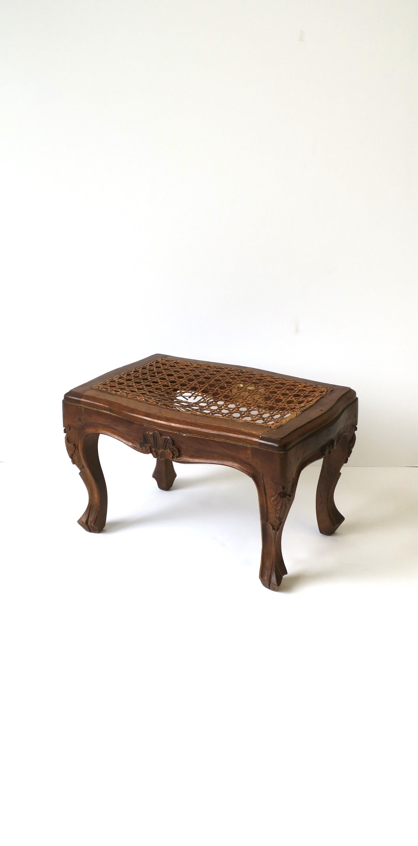 An Italian cane top wood stool / footstool with carving detail and cabriole leg in the Rococo style, circa mid to late-20th century, Italy. Piece was made for Neiman Marcus as per label on underside and as shown in last image. Piece can also be used
