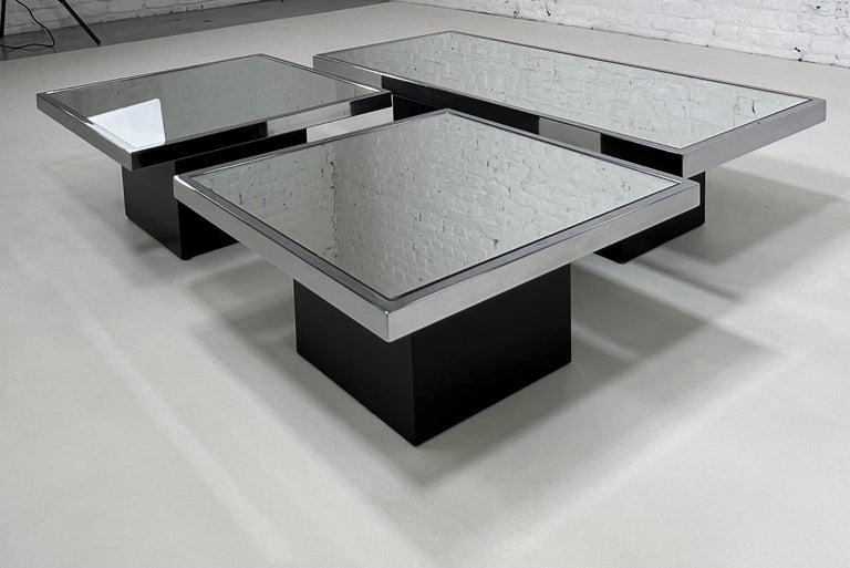 Italian Willy Rizzo 1960 - 1970s design coffee tables set composed of two squared coffee or side tables and a larger rectangular one with black wooden bases, chrome outlined and mirrored glass tops.
Dimensions of the rectangular table are H33 x W124