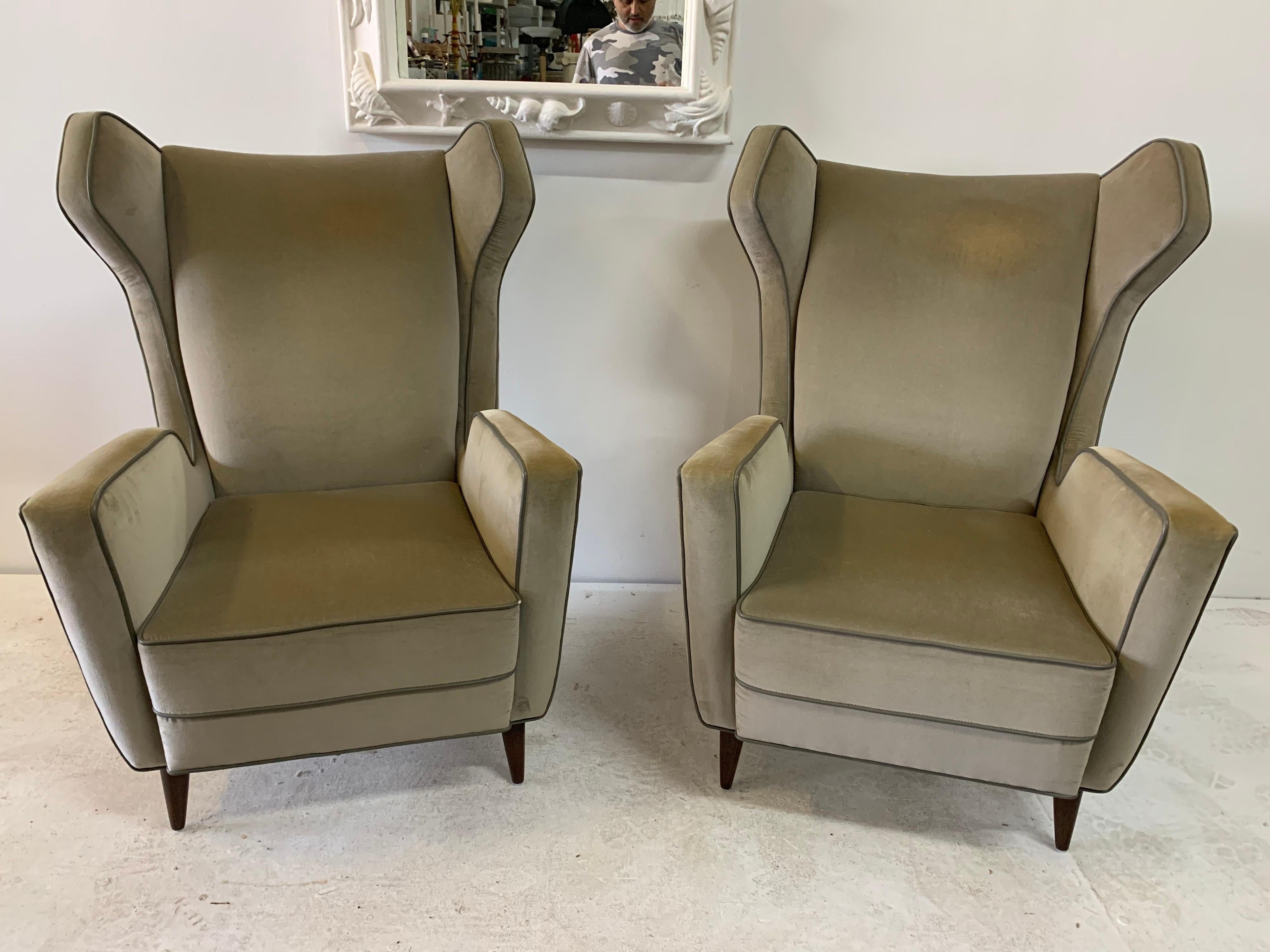 Really clean and defined lines, these armchairs with sculptural winged headrest and turned wood feet, are upholstered in a heather velvet with dark gray leather piping. Very comfortable. Note: We do have a professional upholstery service if you